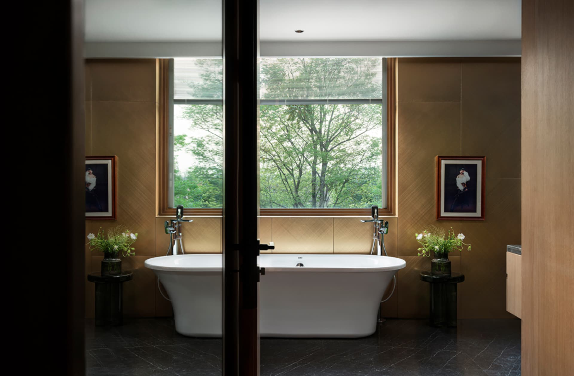 A clean, minimalist bathroom with a large white ceramic tub, framed by large windows and surrounded by brown walls.