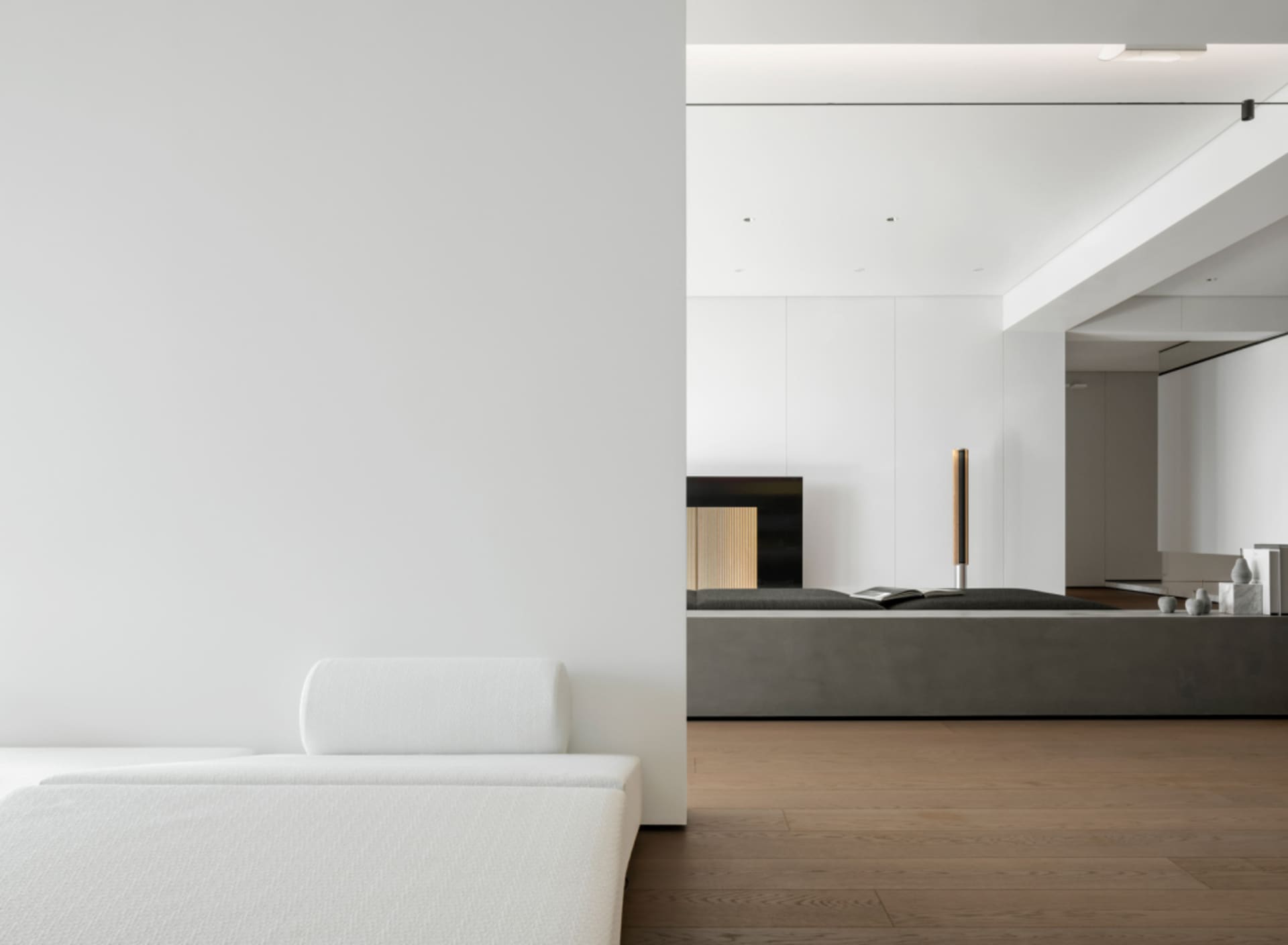 Modern minimalist living room with concrete walls, wooden floors, and metallic accents.