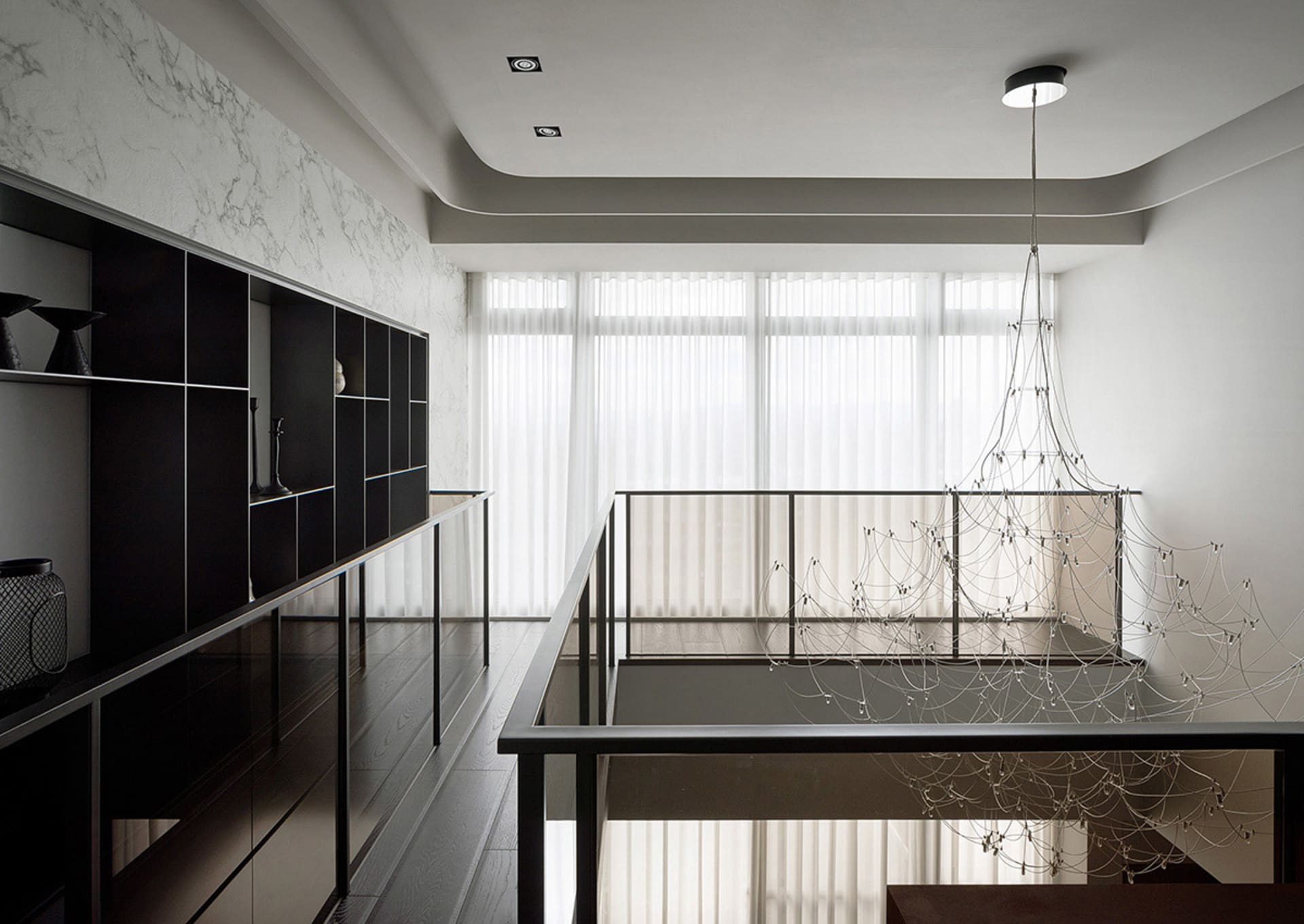 Modern residential interior with a sleek, black metal staircase featuring a white metal handrail and a matching black metal r