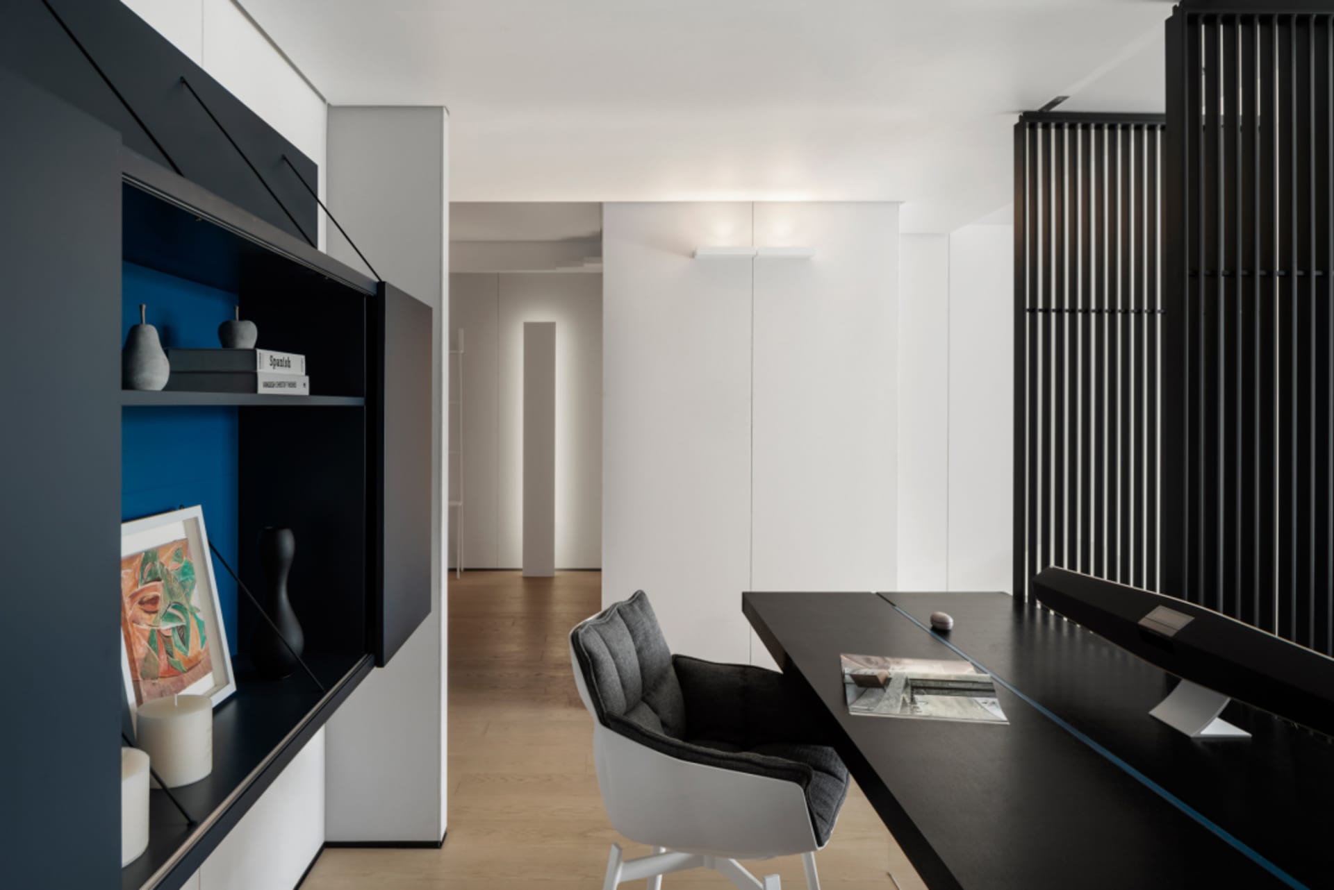 Modern home office with a sleek black desk, white chair, and minimalist design elements.