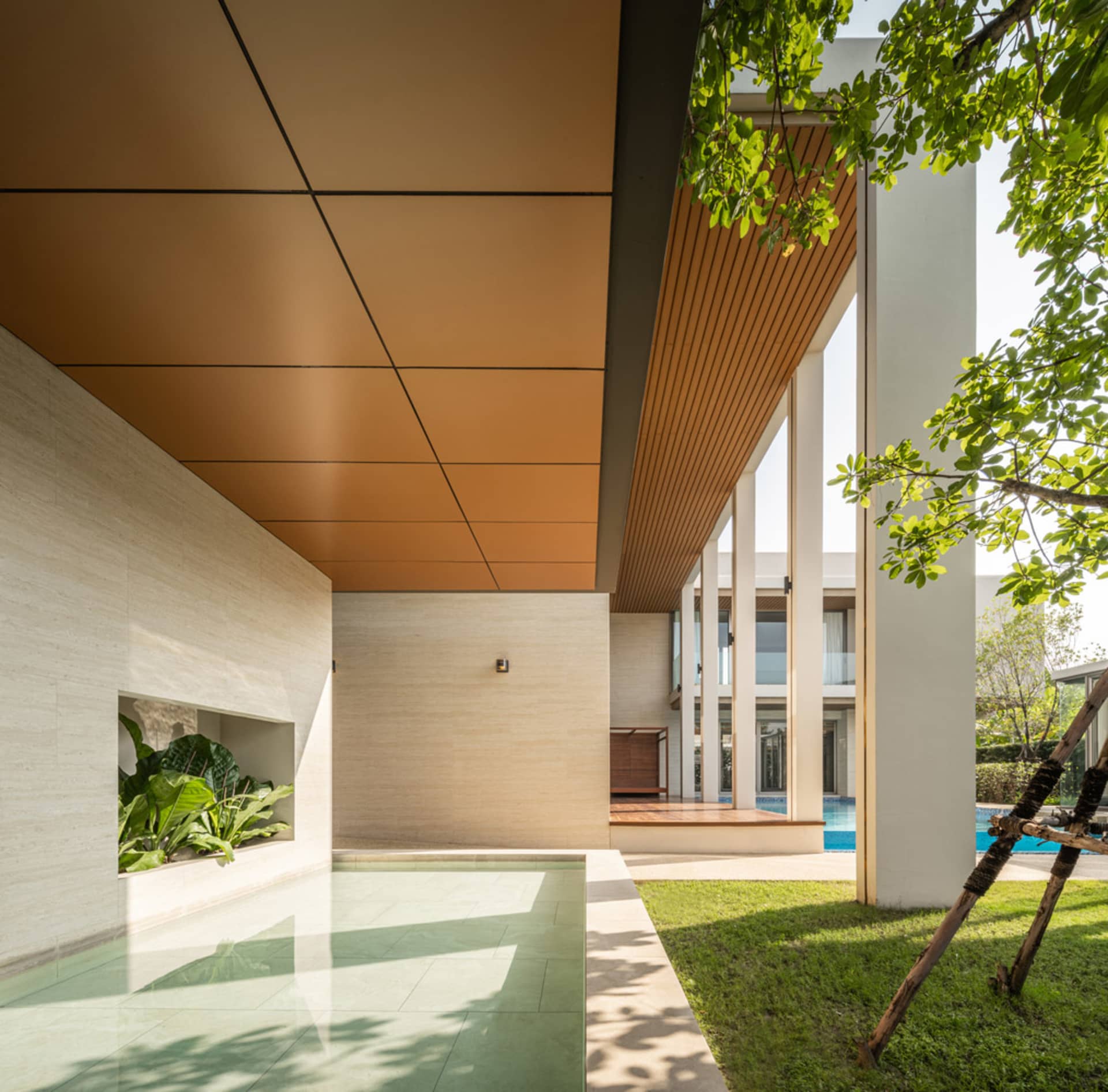 Modern architectural house with concrete walls and floor, featuring a pool and greenery.