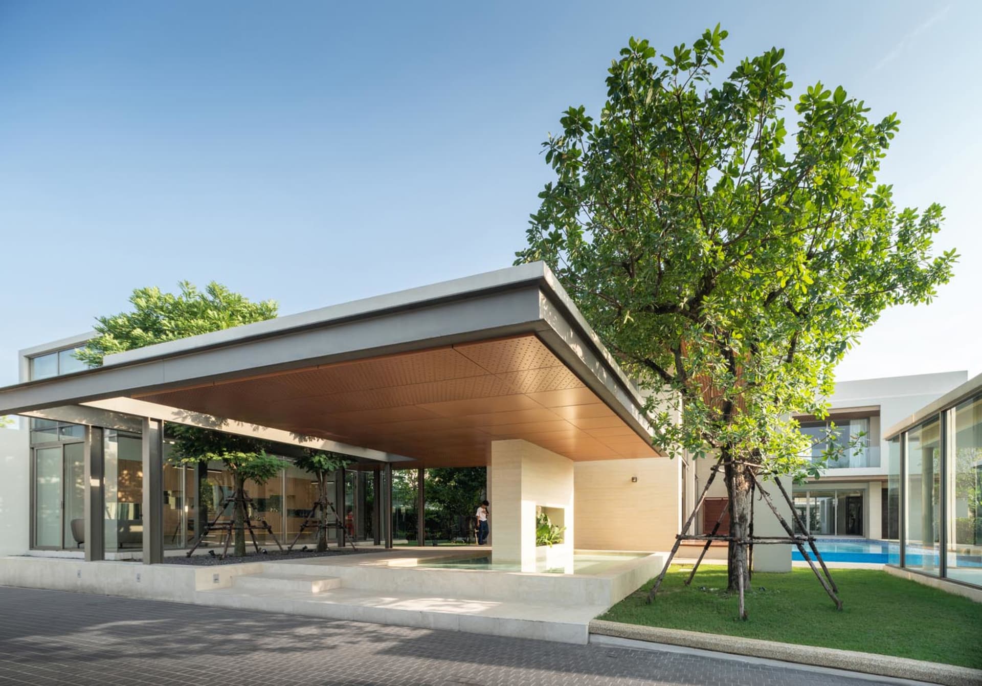A modern residential building with a steel and glass facade, featuring a spacious outdoor patio and a swimming pool.