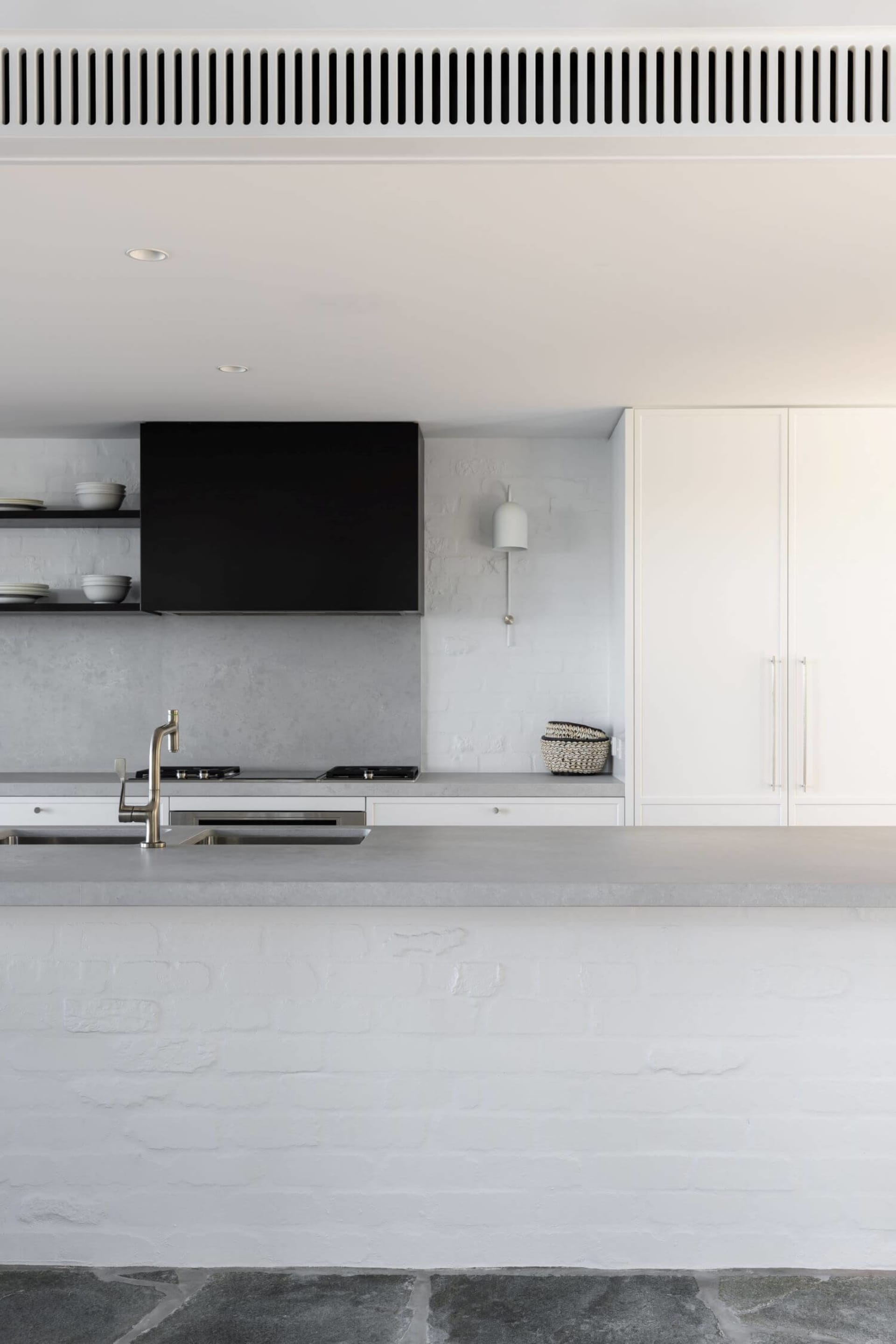 Modern kitchen with concrete countertops and white brick walls.