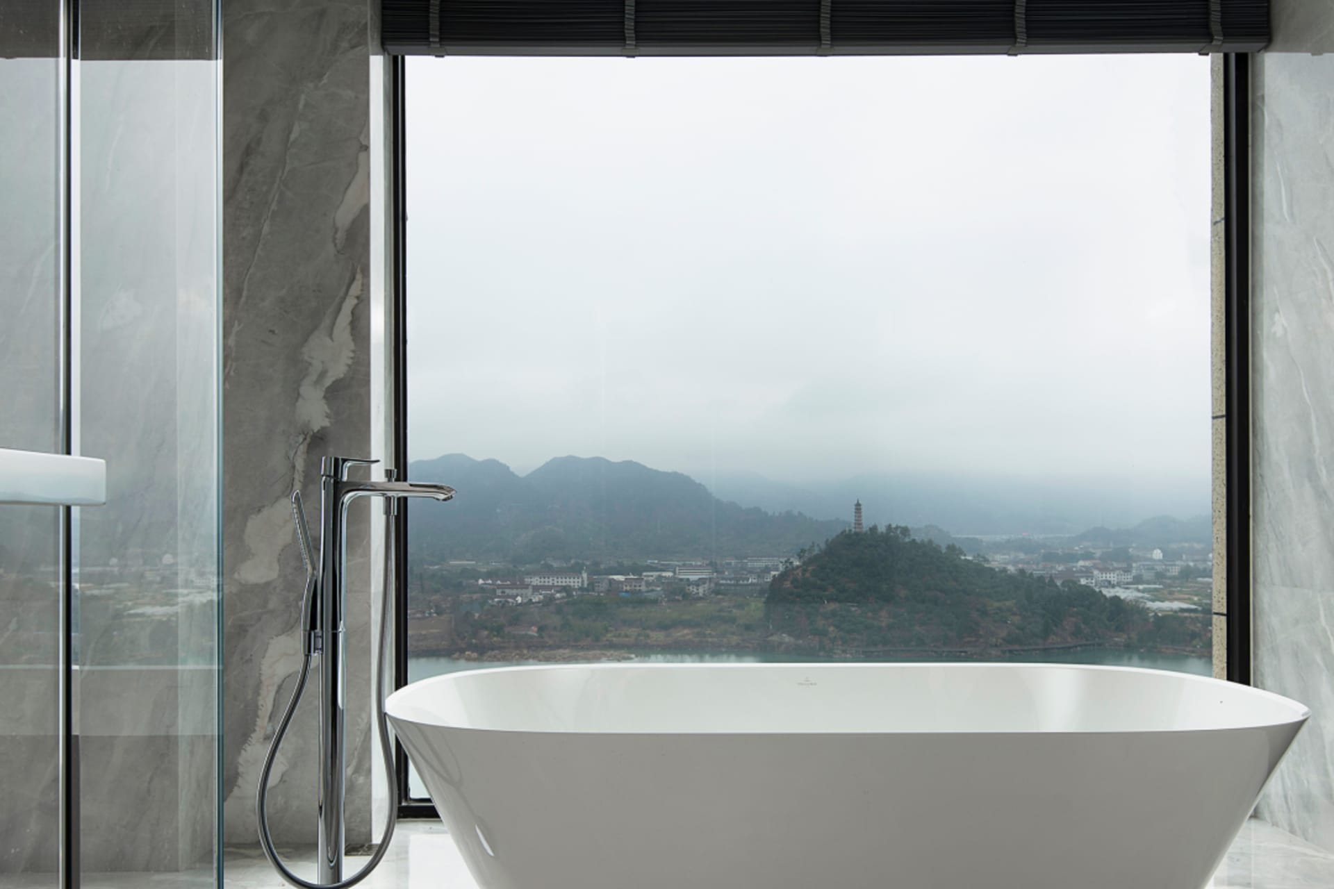 Modern residential bathroom featuring marble and ceramic finishes with a scenic view.