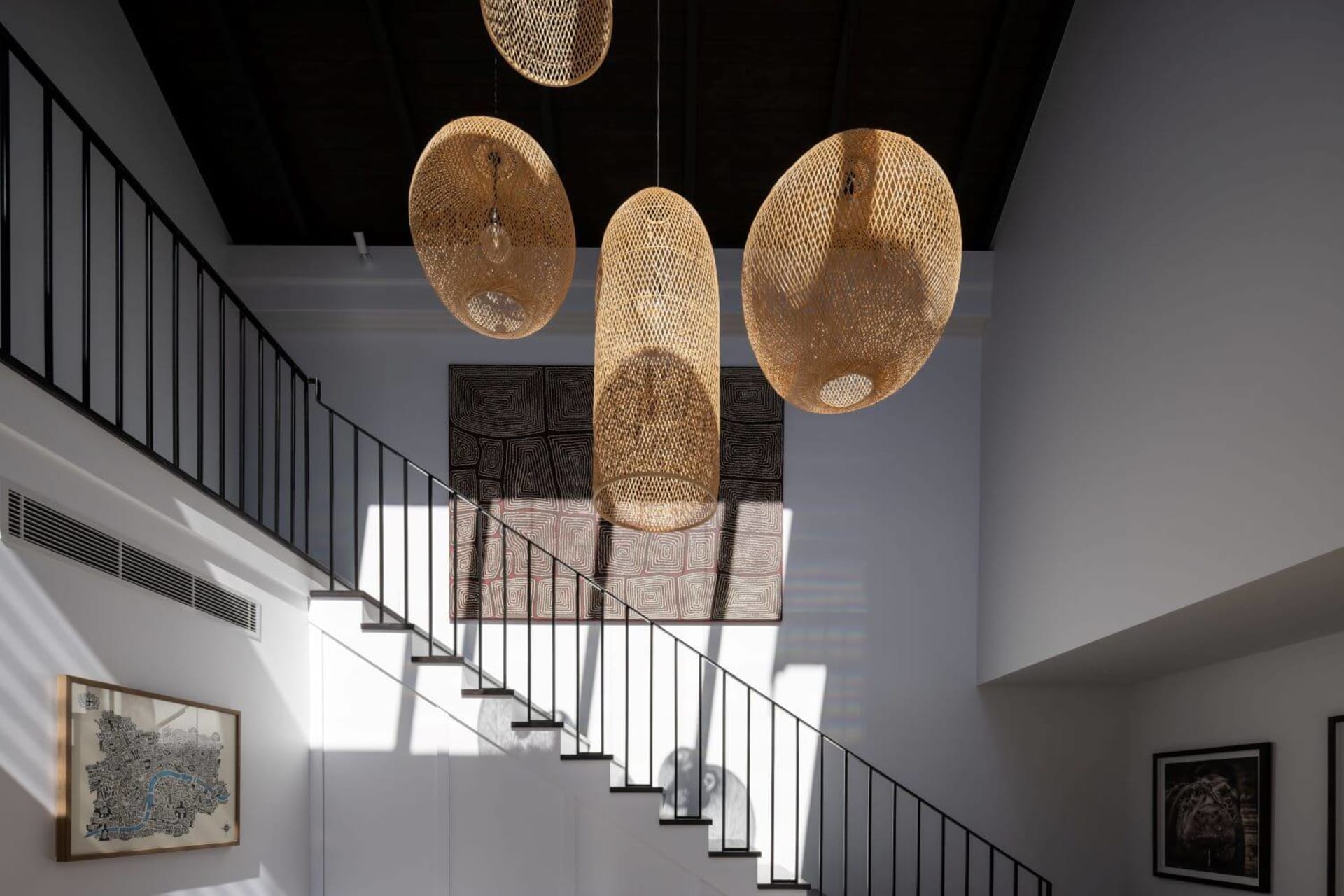 A staircase interior with four large, woven straw pendant lights hanging from the ceiling.