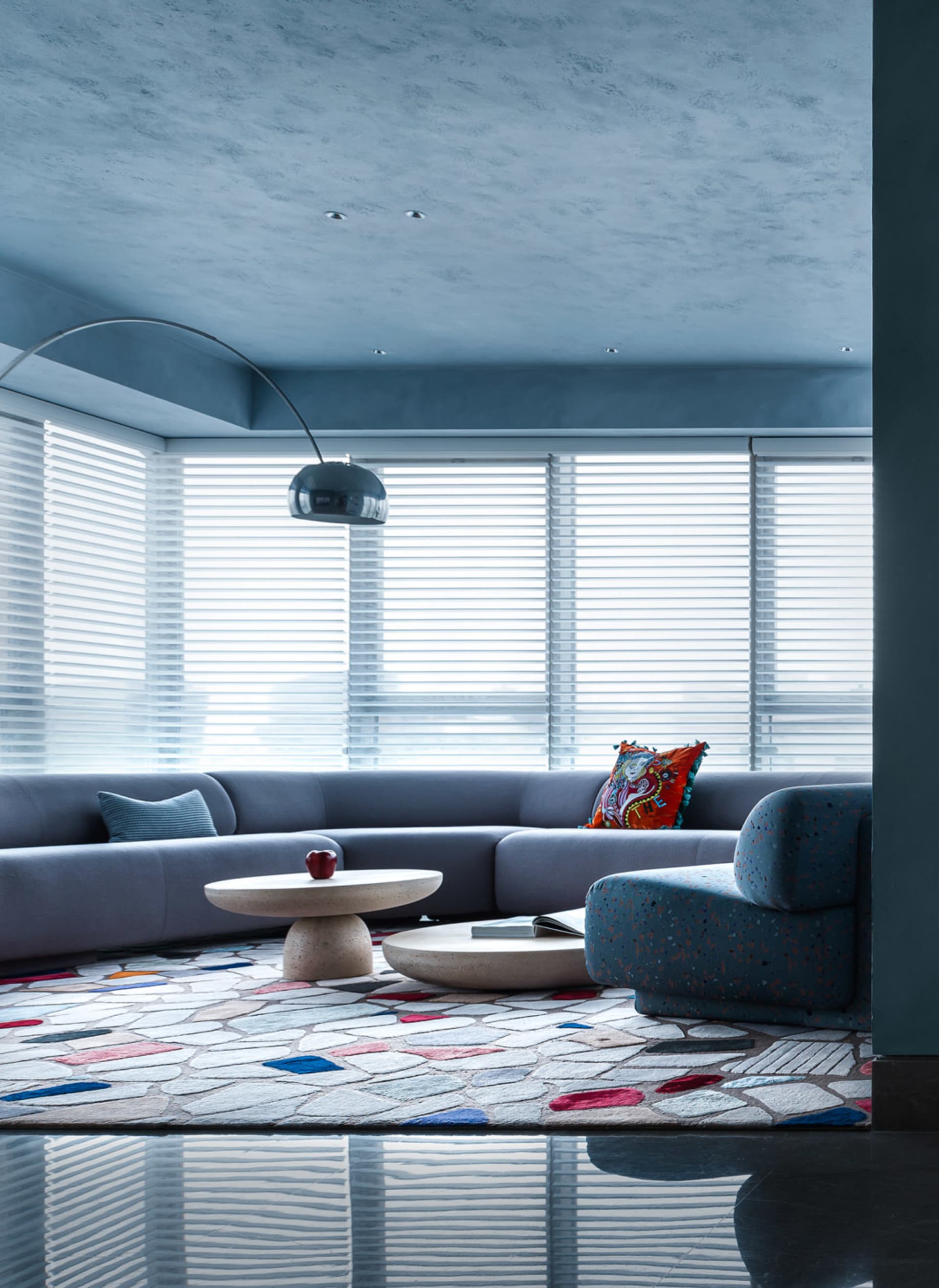 A modern living room featuring a terrazzo rug, contemporary furniture, and a floor lamp.