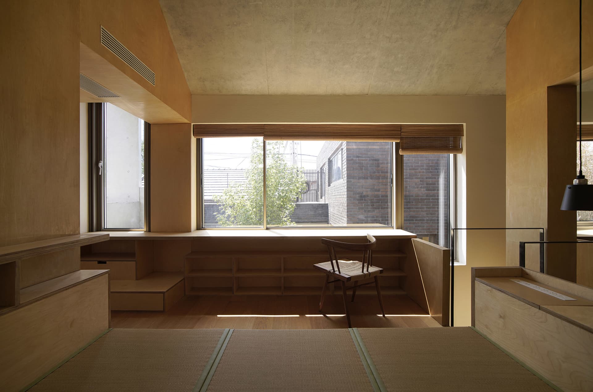 A minimalist room with wooden and bamboo materials, a large window, and a wooden chair.