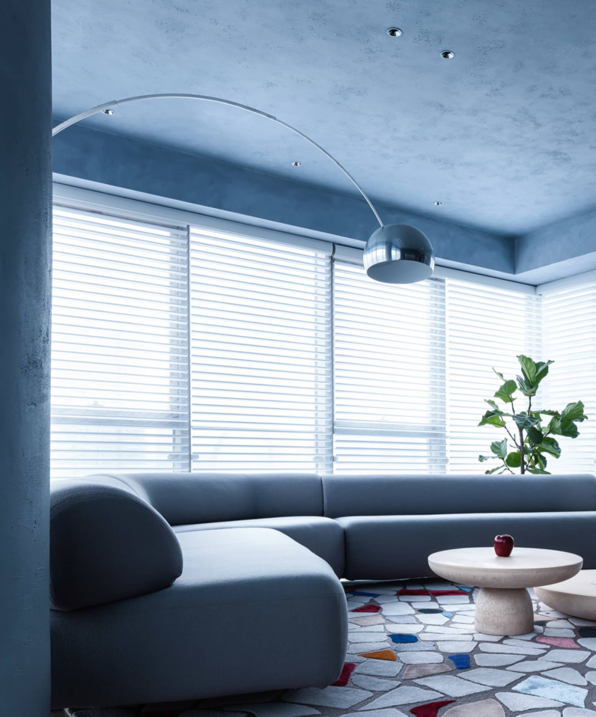Contemporary living room interior with grey sectional sofa, glass coffee table, and modern floor lamp.