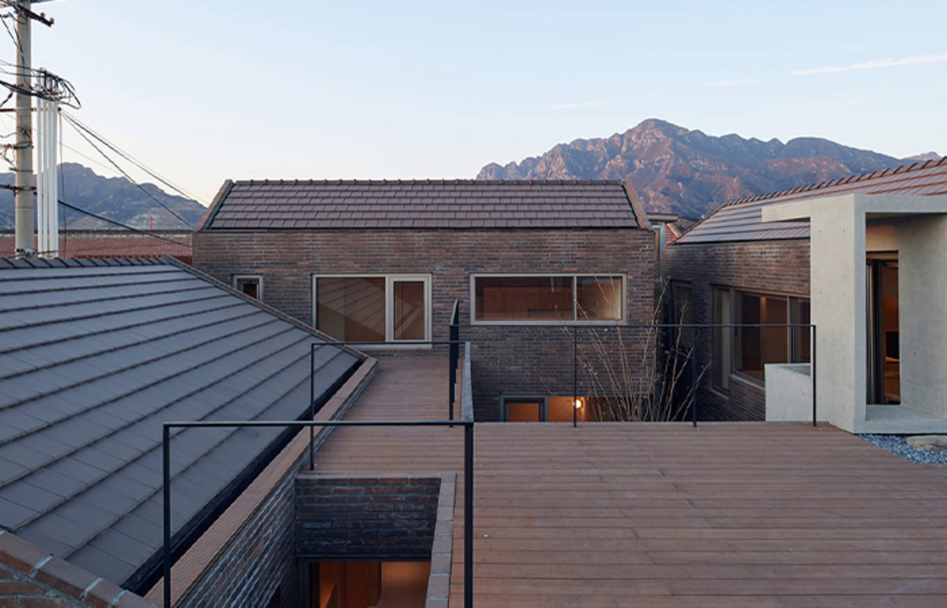 A rooftop view of a modern residential building with brick and tile roofing, and concrete flooring.