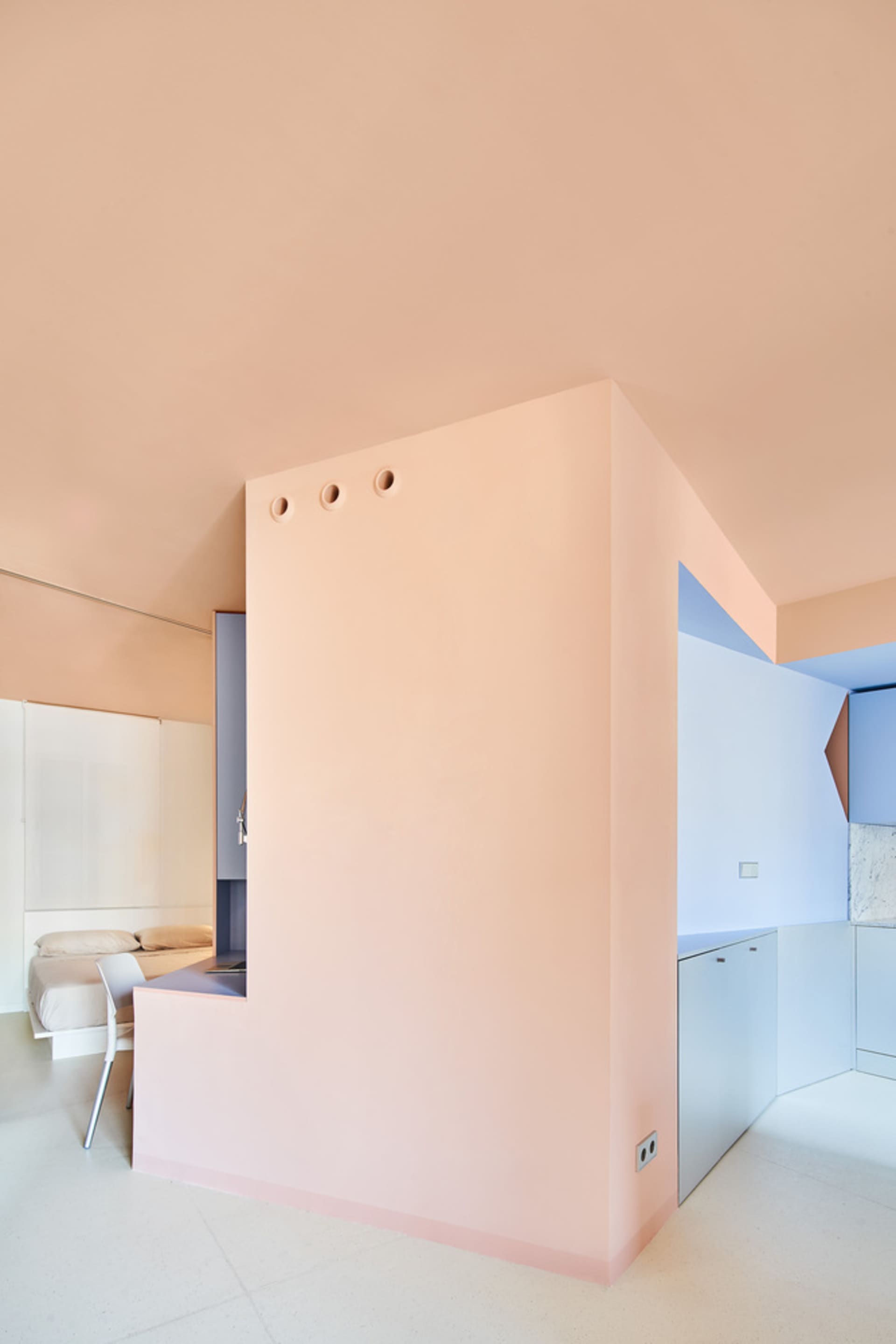 A modern minimalist residential interior with a pink wall and minimal decor.