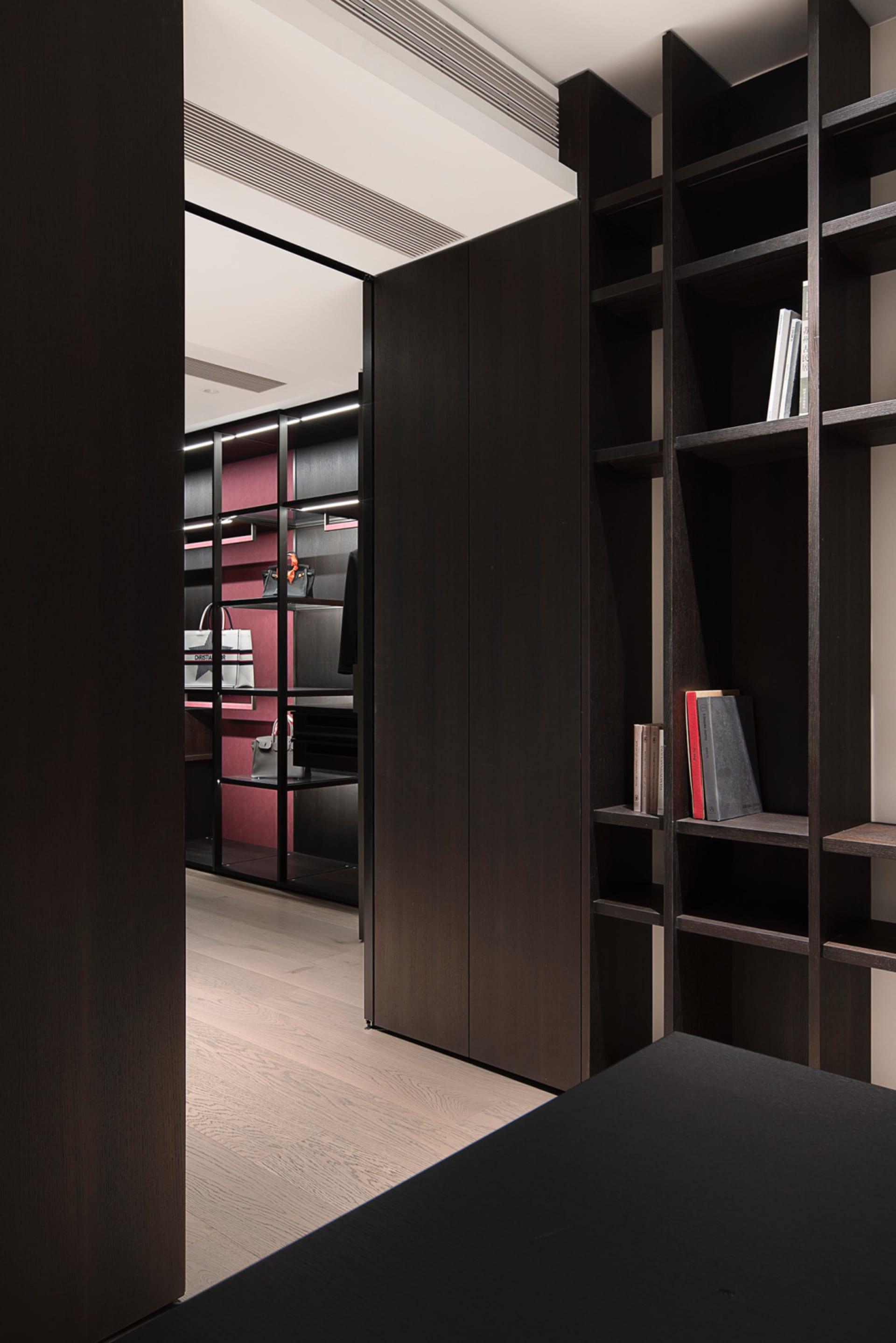 Modern interior design featuring a dark wooden wardrobe and a matching wooden bookshelf.