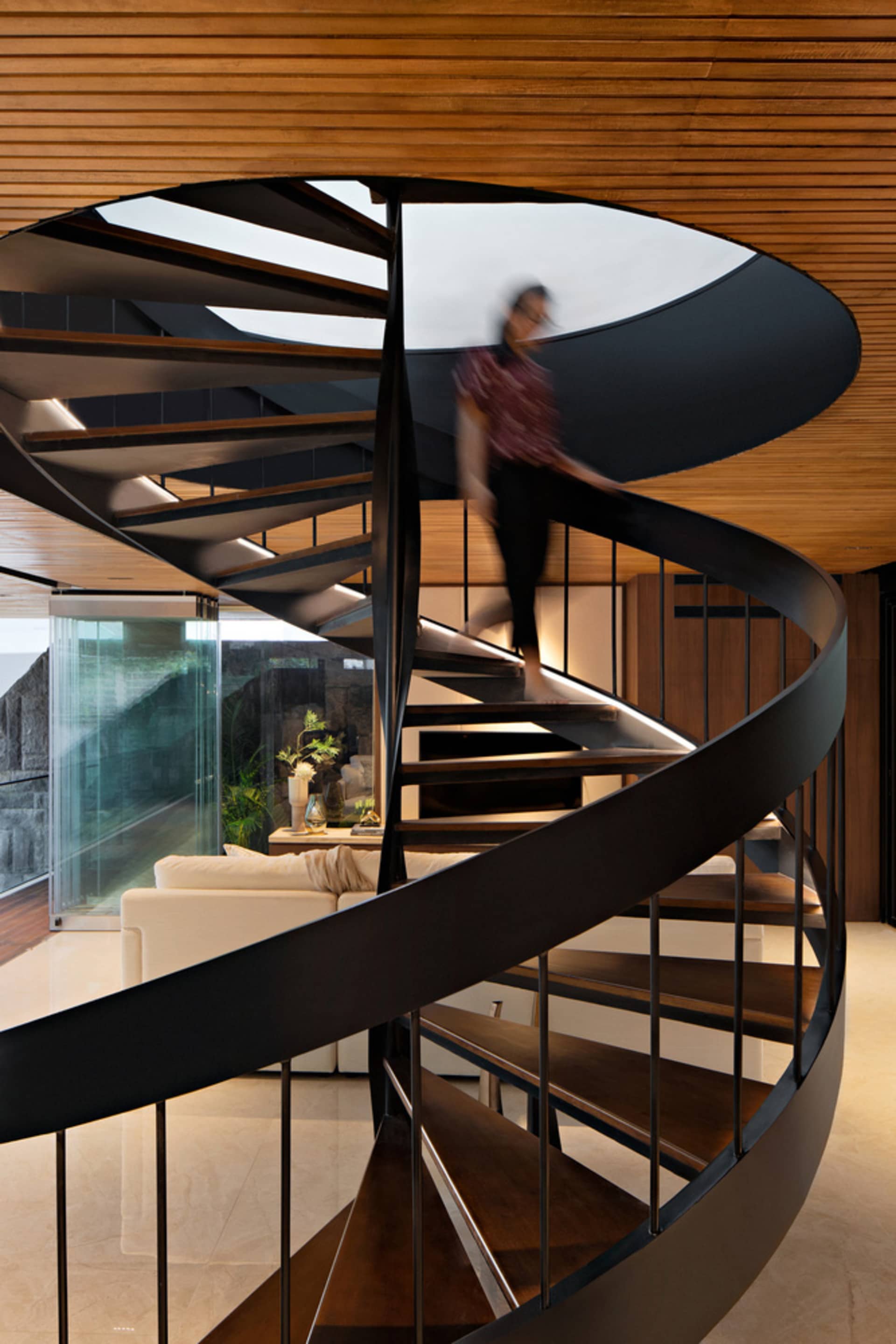 A modern residential interior featuring wooden floors, metal railings, and glass windows.