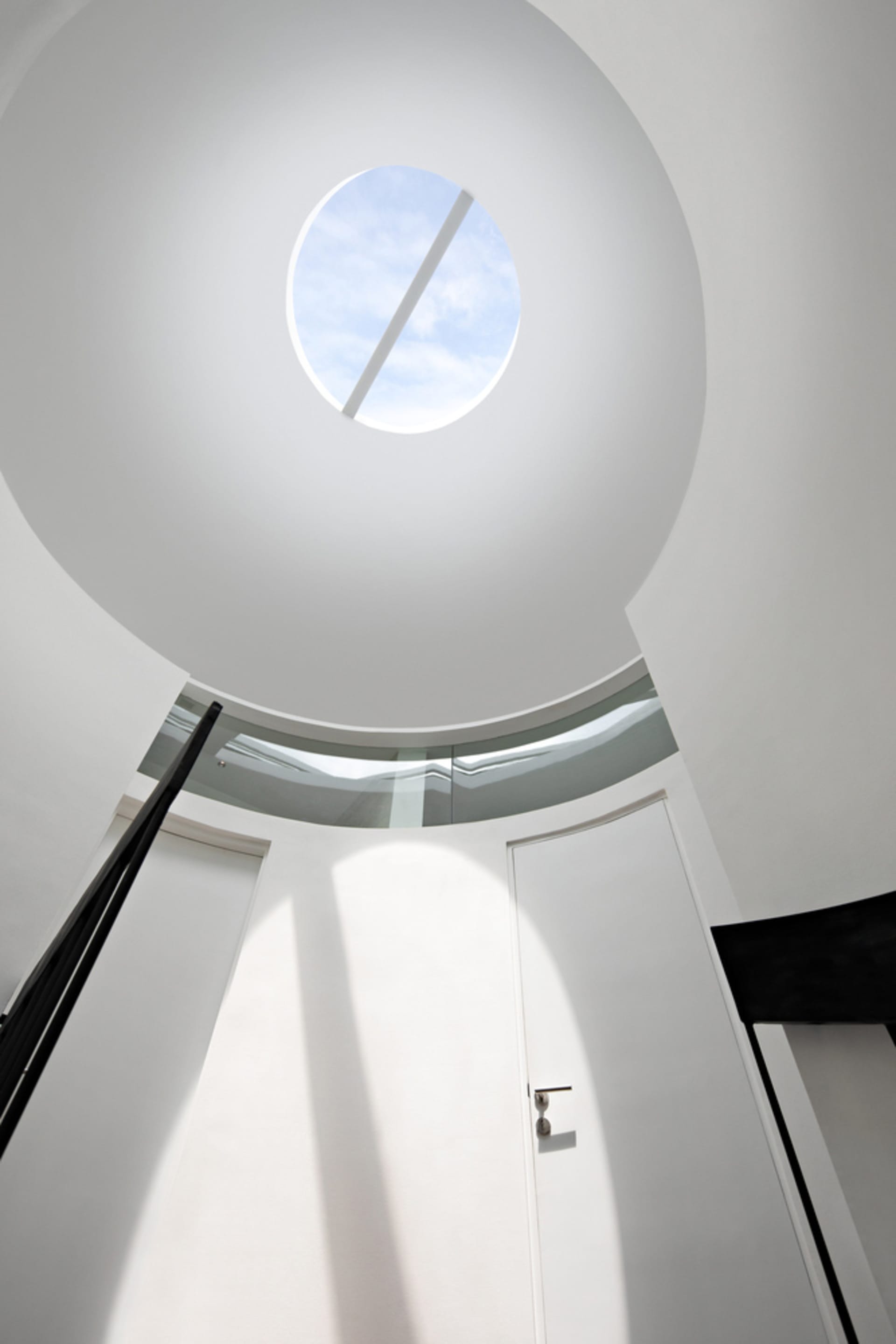 A modern white space with a glass ceiling allowing natural light to flood the area.