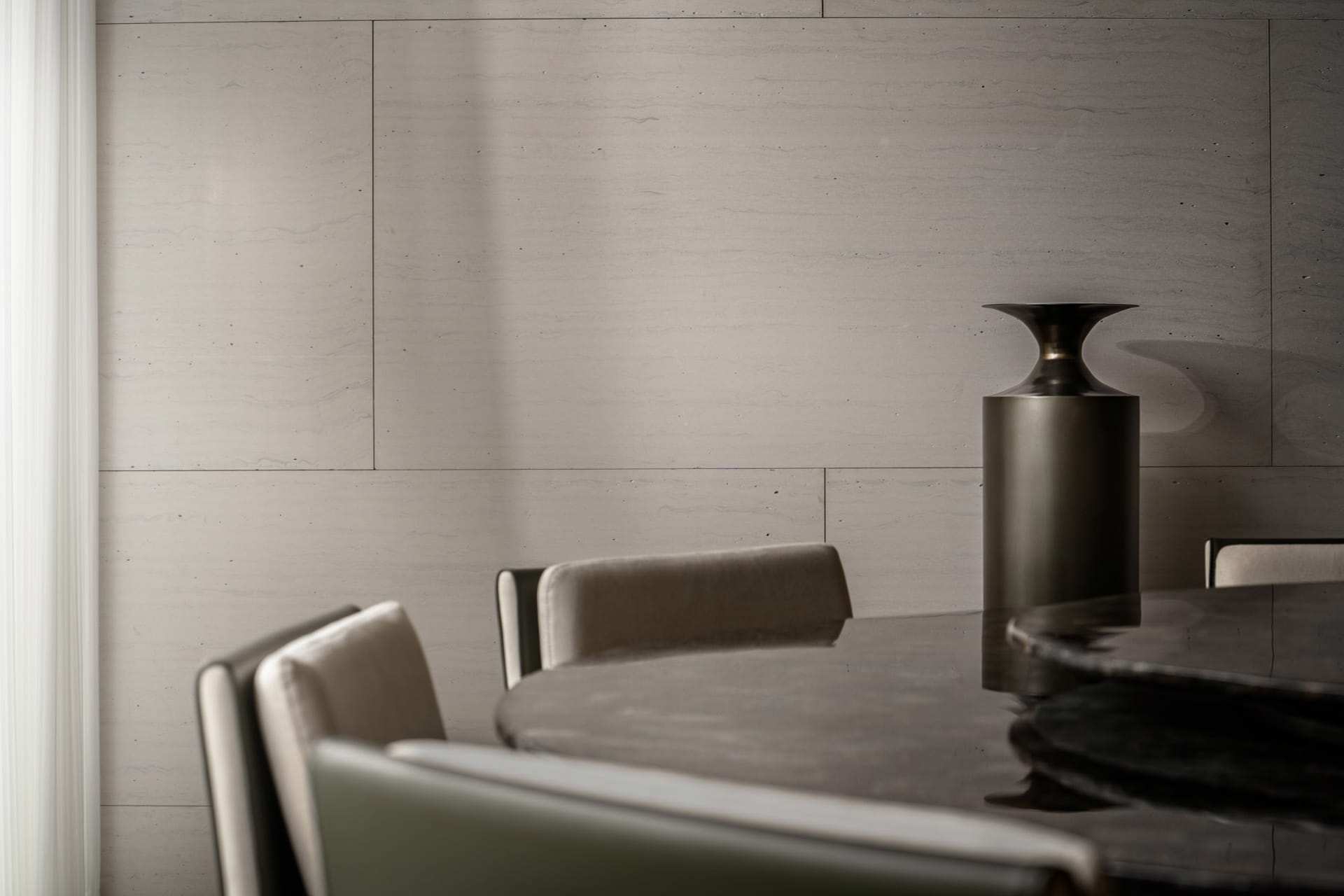 A modern dining room featuring a sleek, black marble dining table surrounded by contemporary chairs, with a minimalist aesthe