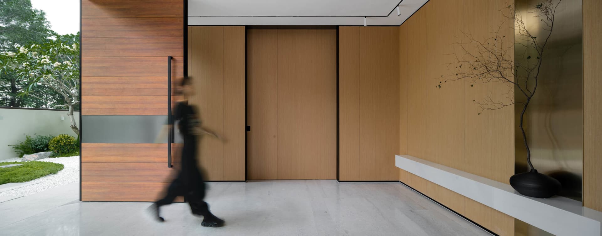 A modern entrance featuring a large wooden door with glass panels and a polished concrete floor.