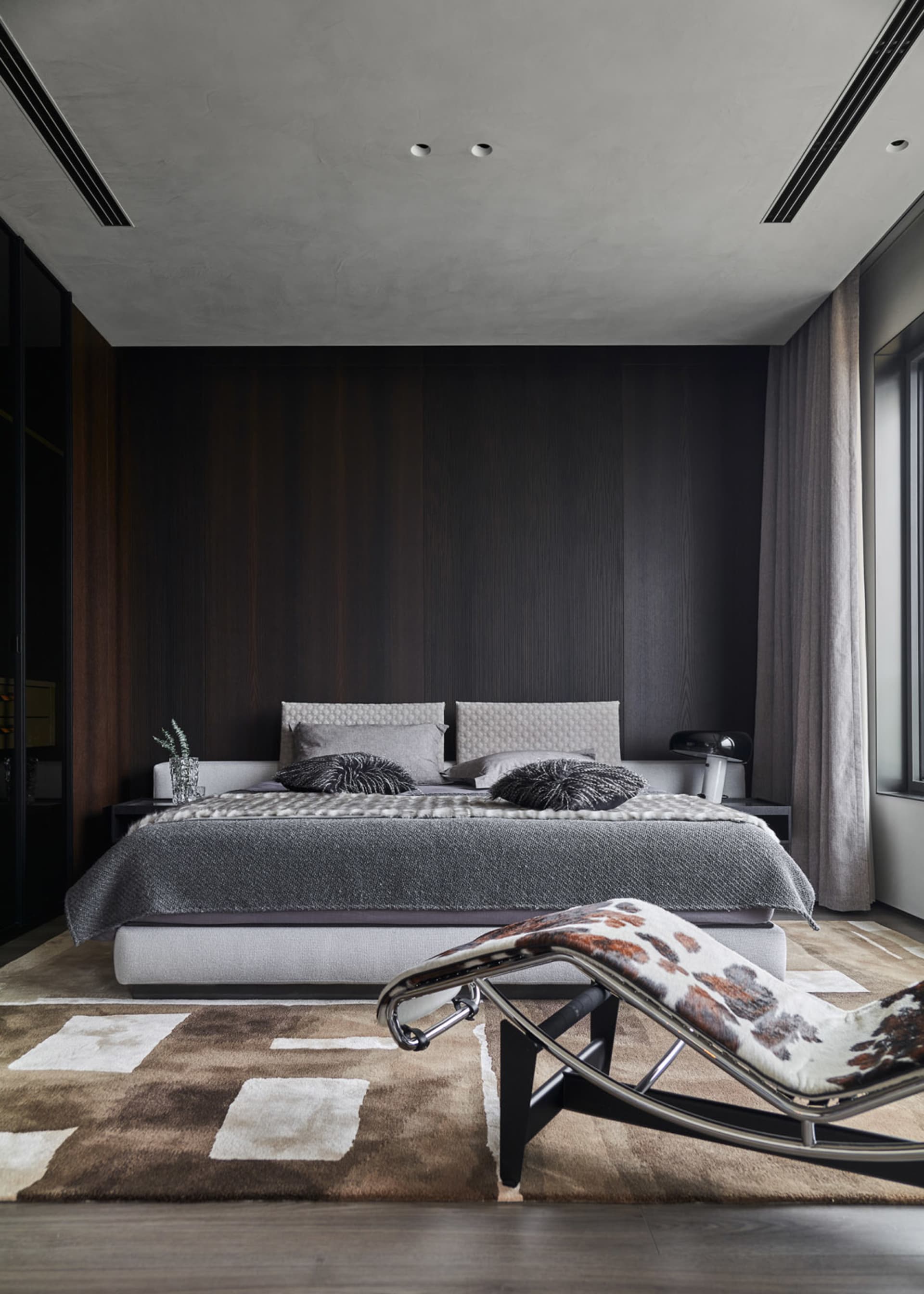 A modern minimalist bedroom featuring a bed with pillows and blankets