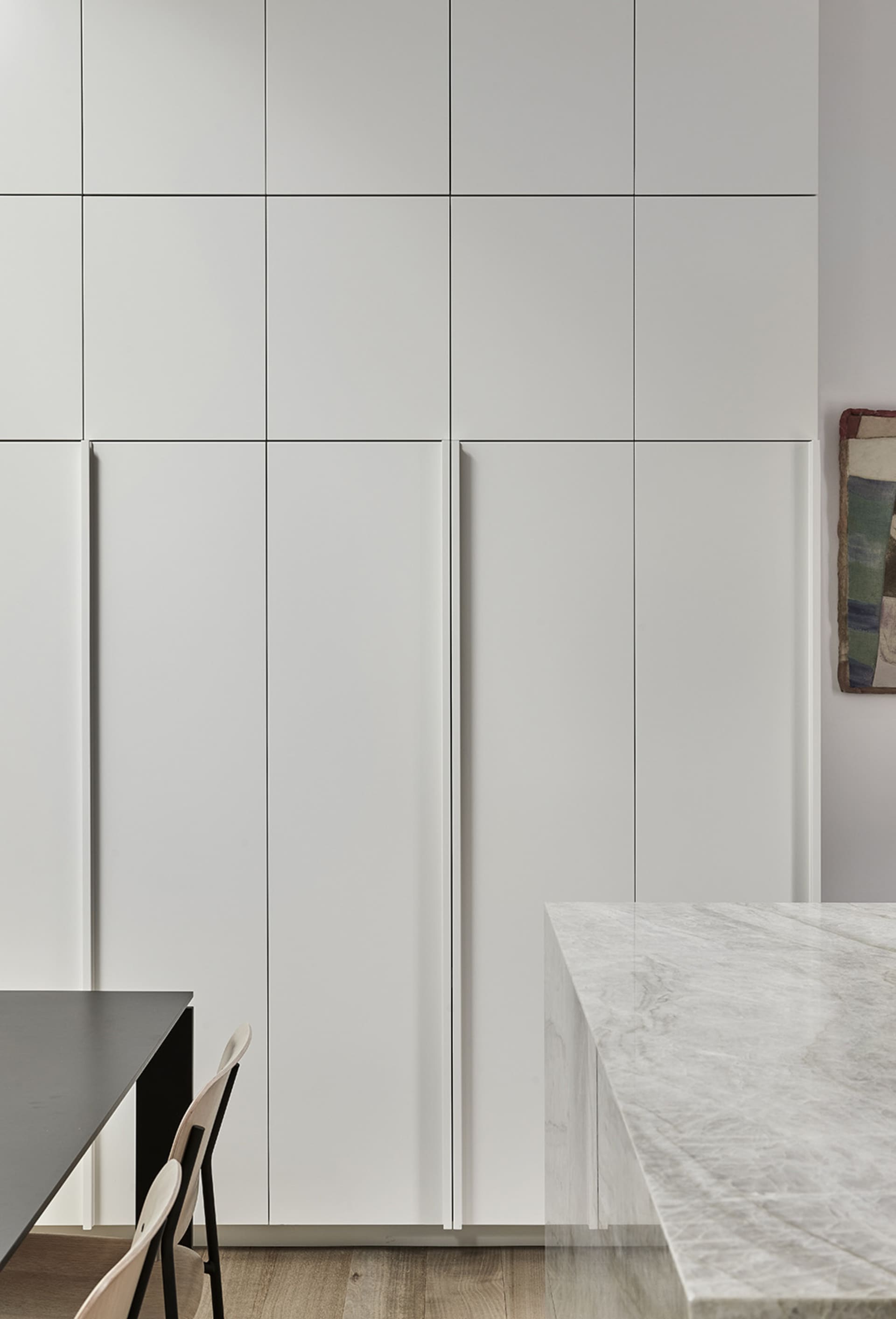 Minimalist kitchen featuring white marble countertops and cabinets.