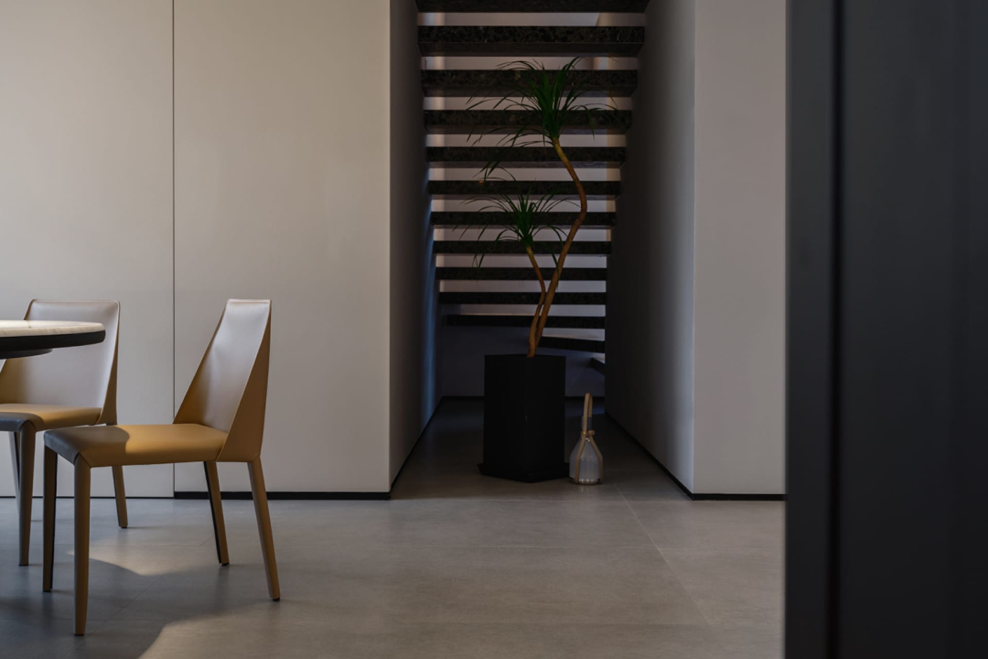 Modern, minimalist home interior with a concrete staircase and sleek, minimalist furniture.
