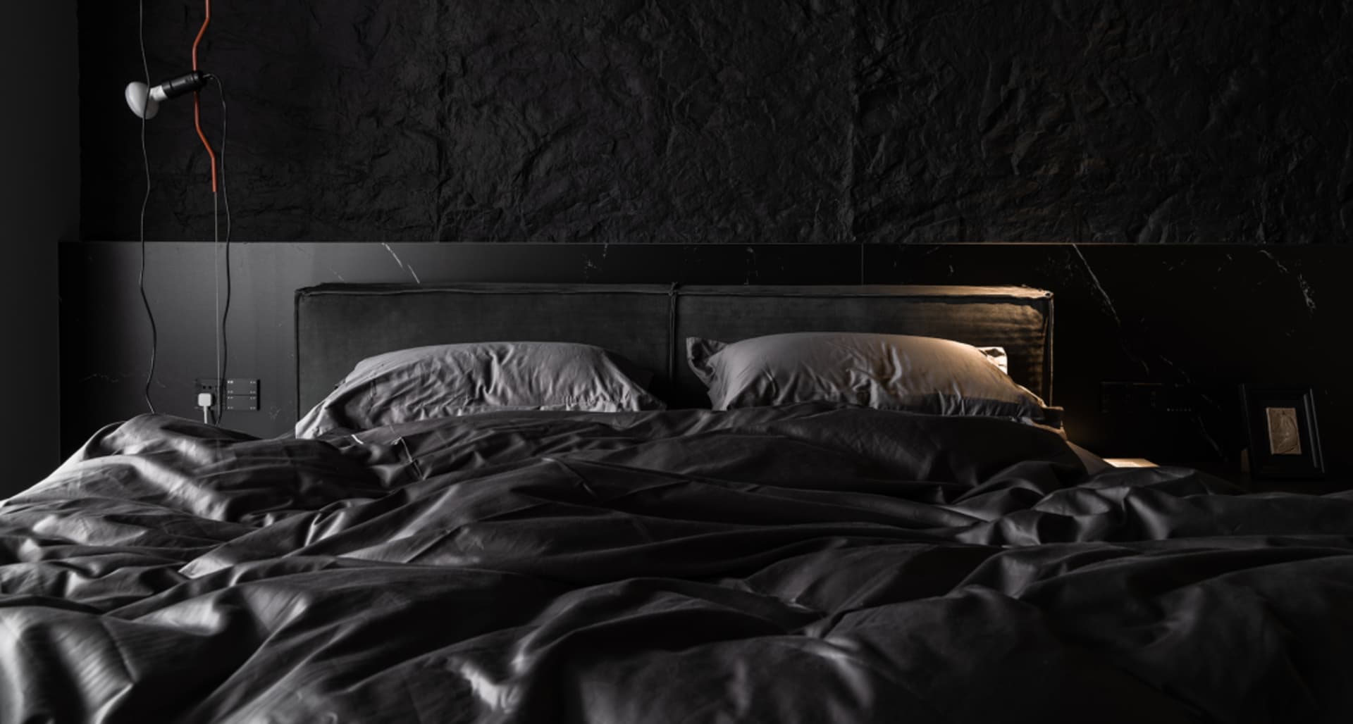 Modern minimalist bedroom with black textiles and white lighting