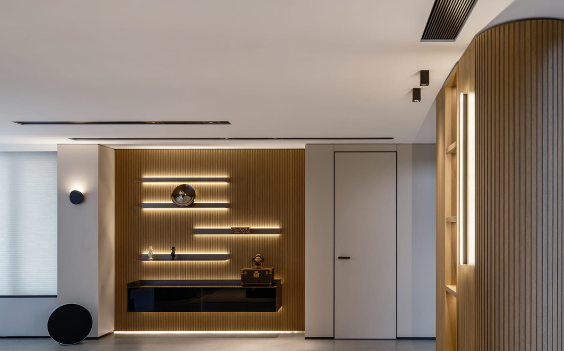 A modern living room featuring wooden walls and shelves with lighting.