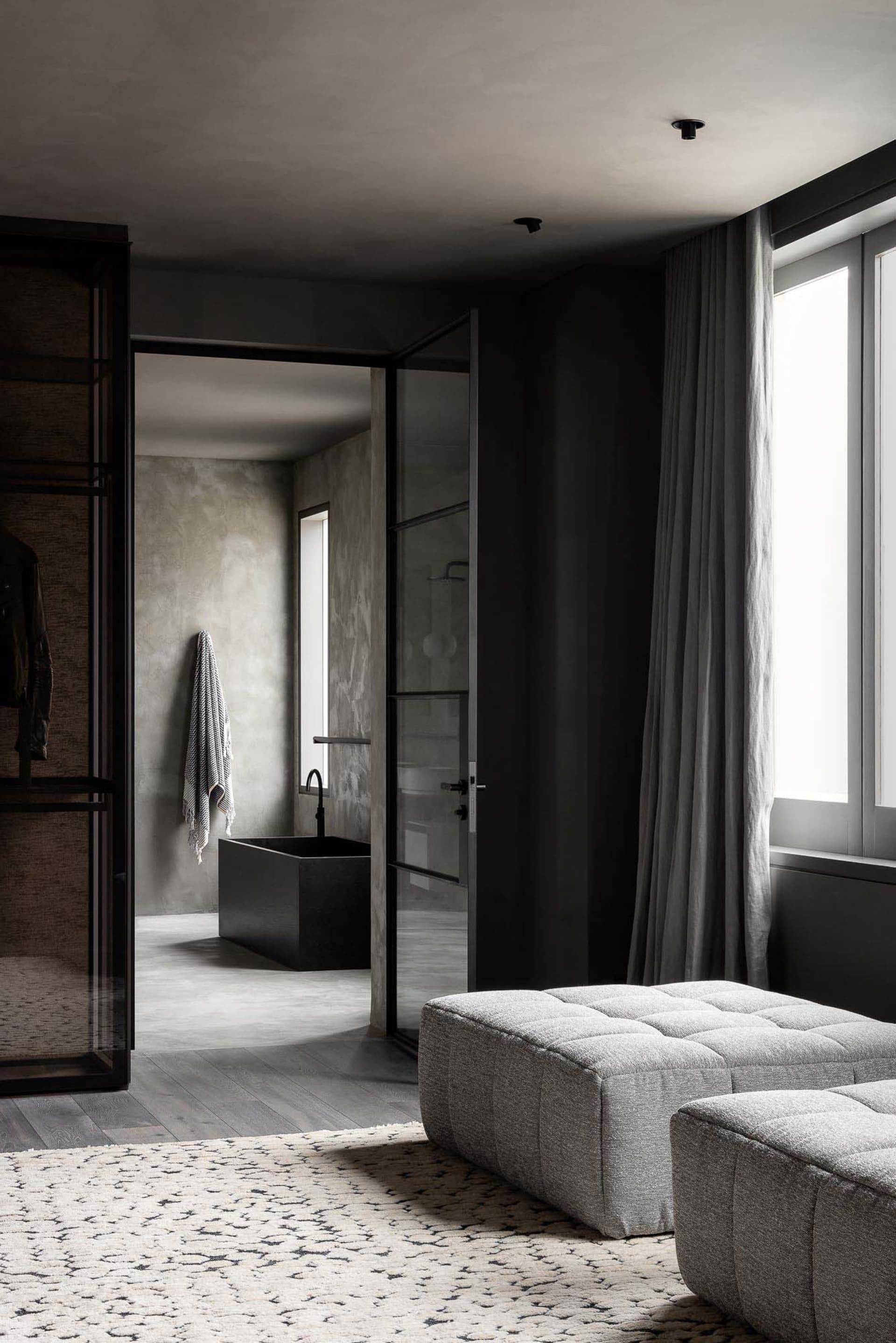 A modern, minimalist bathroom with industrial elements featuring concrete walls and floor, a glass shower enclosure, and a si