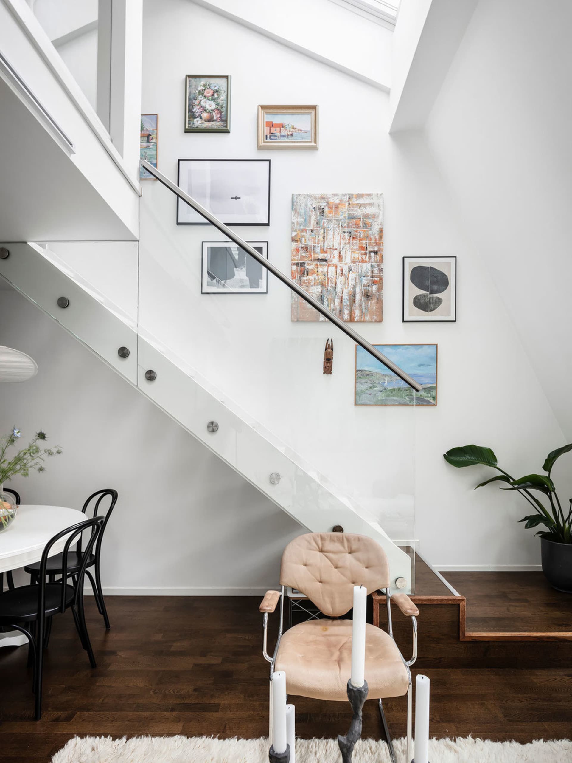 A modern staircase featuring transparent glass steps, a metal frame, and wall art.