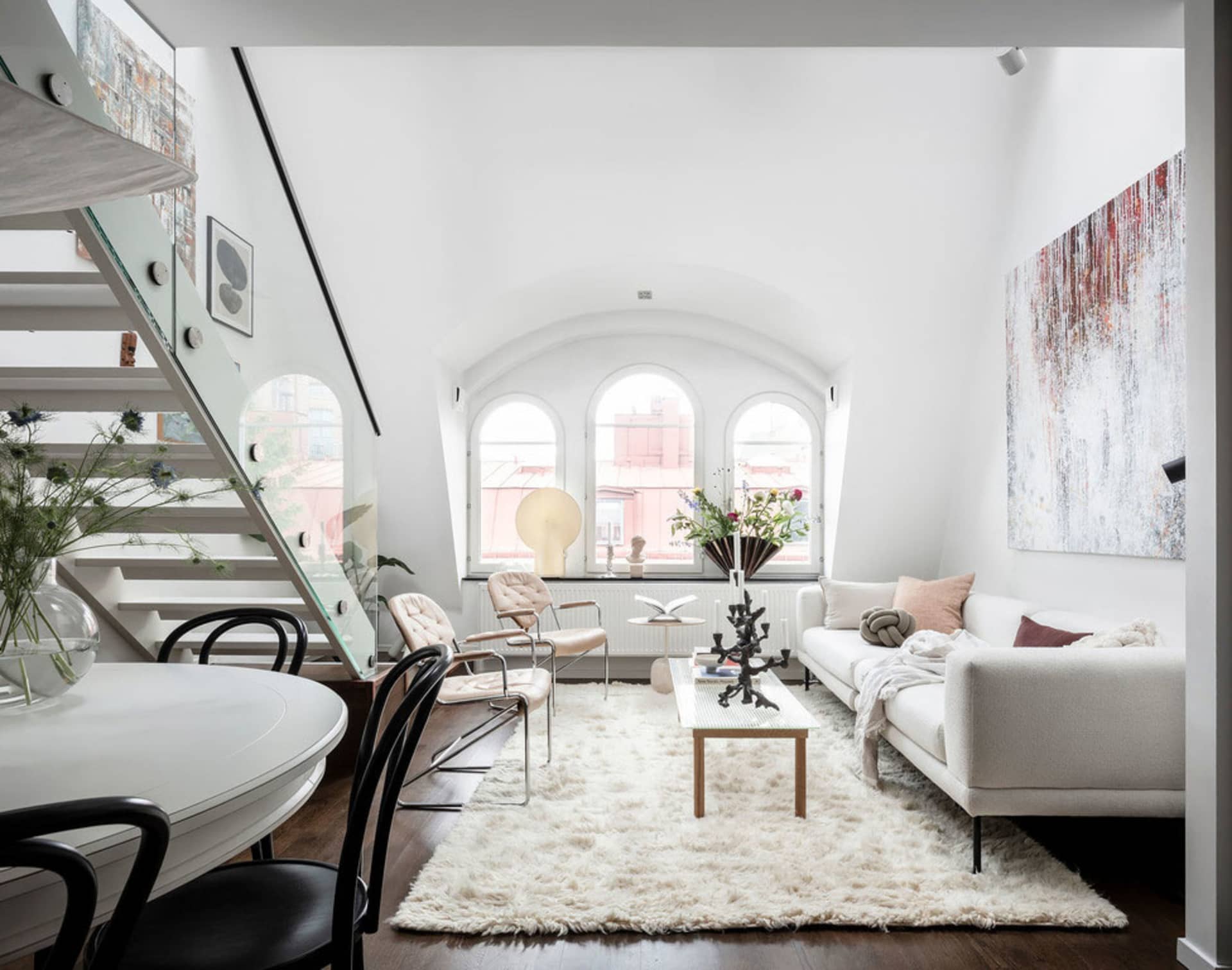 A modern apartment living room with white walls, a white sofa, and a white round dining table.