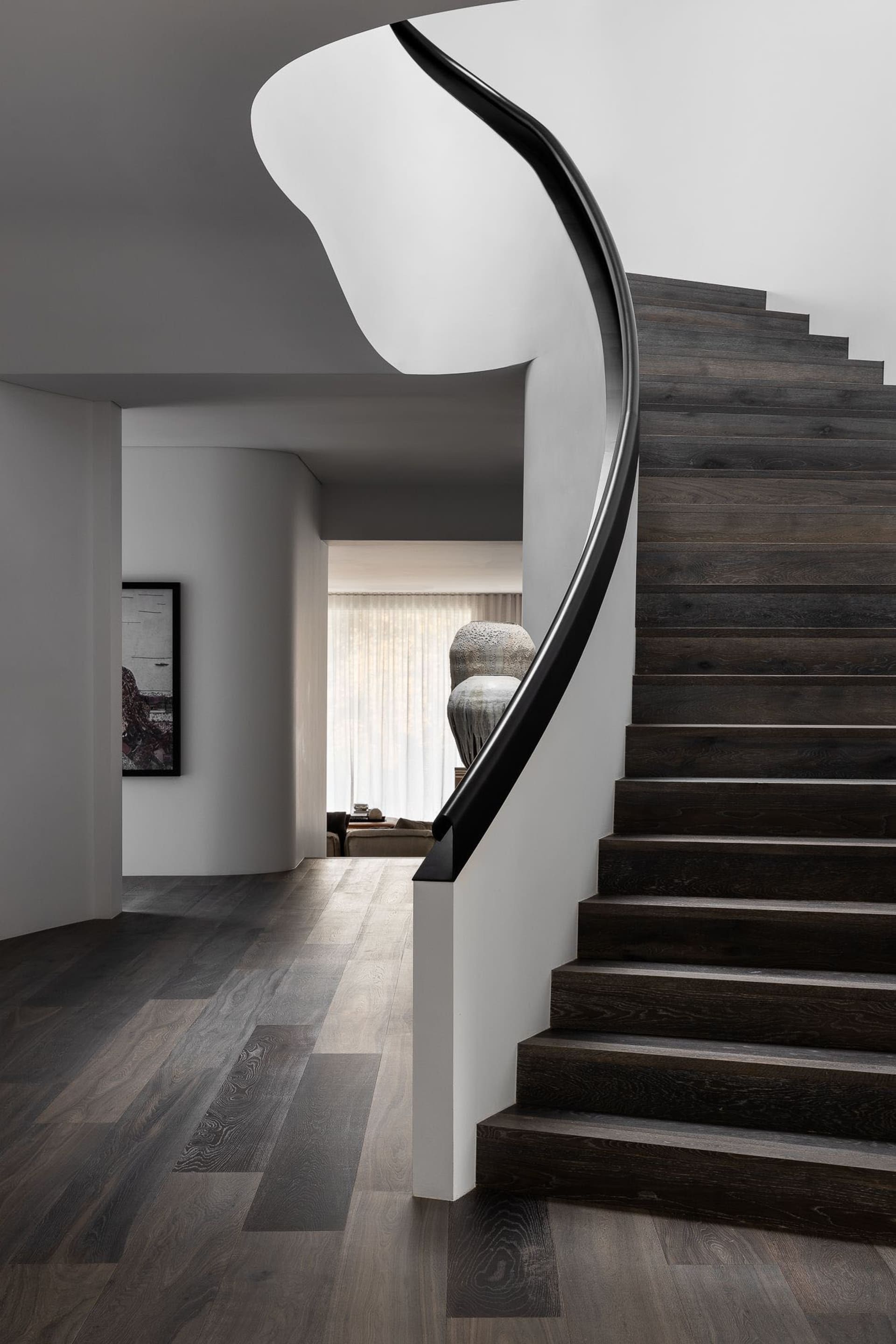 Modern black wood staircase with sleek, curved railings.