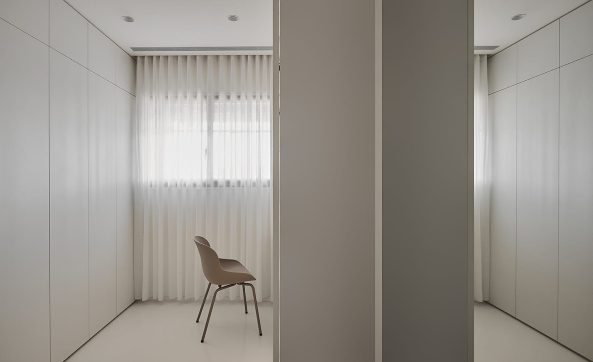 A minimalist wardrobe room with transparent curtains and neutral-color cabinets.