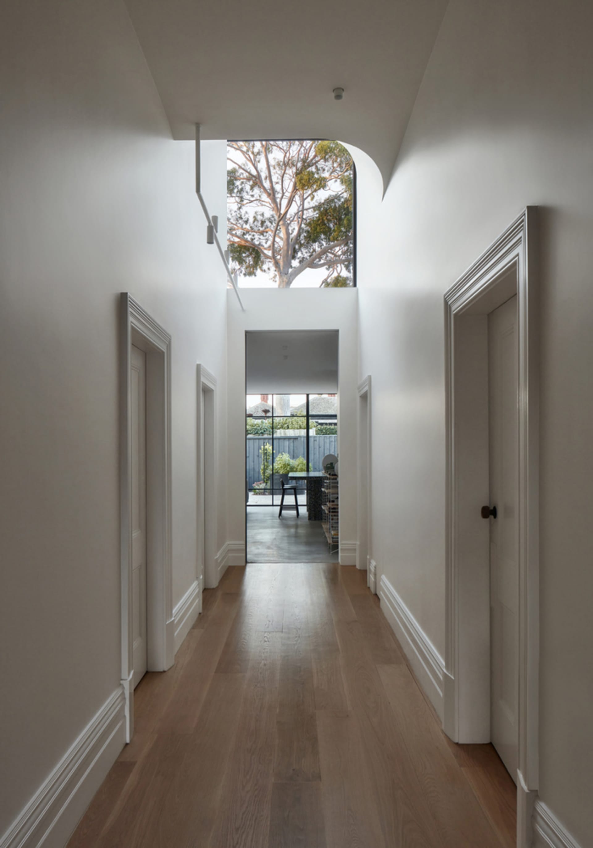 Modern white interior design hallway with hardwood floors and natural light from skylight.