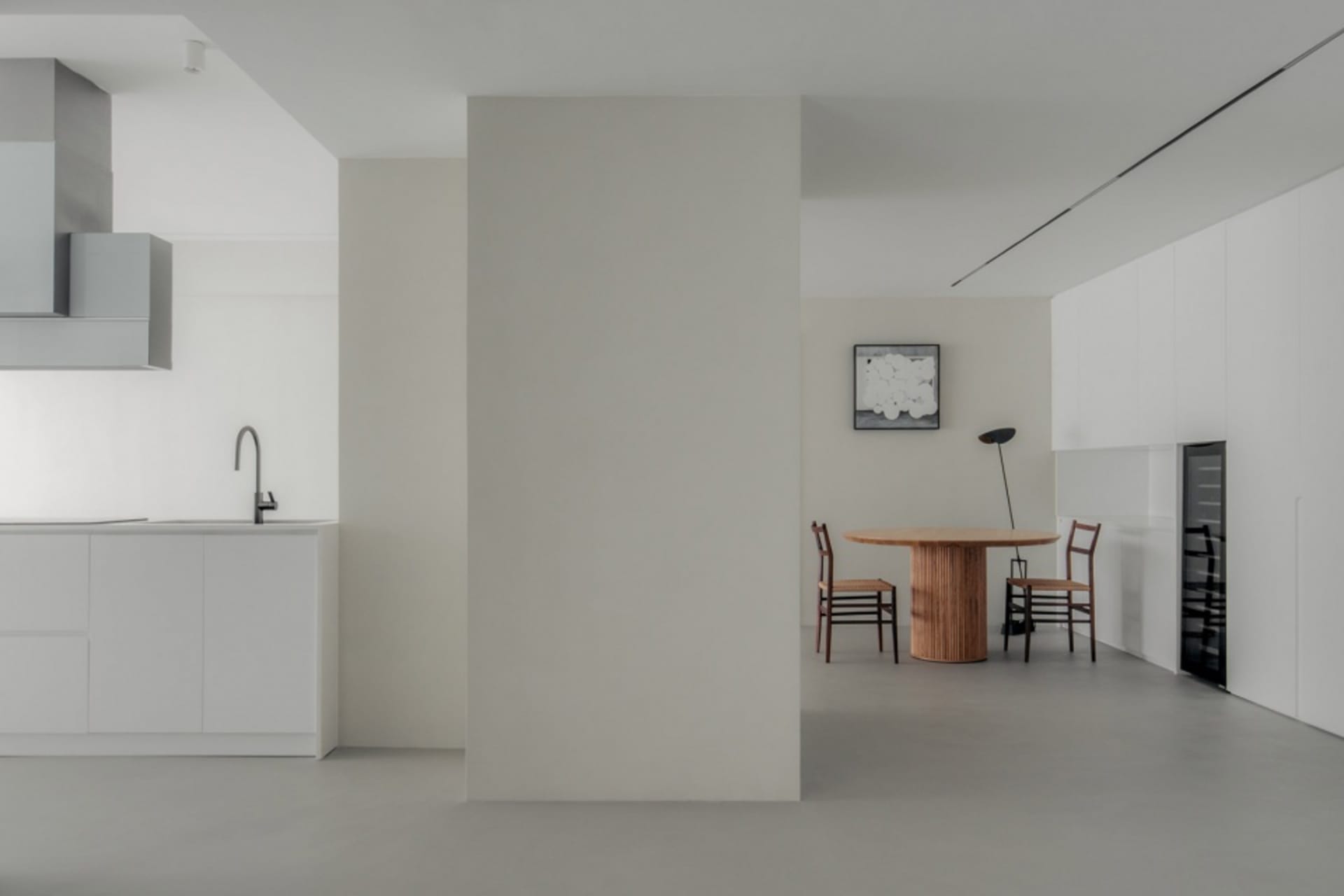 A minimalist kitchen with white cabinets and wooden flooring.