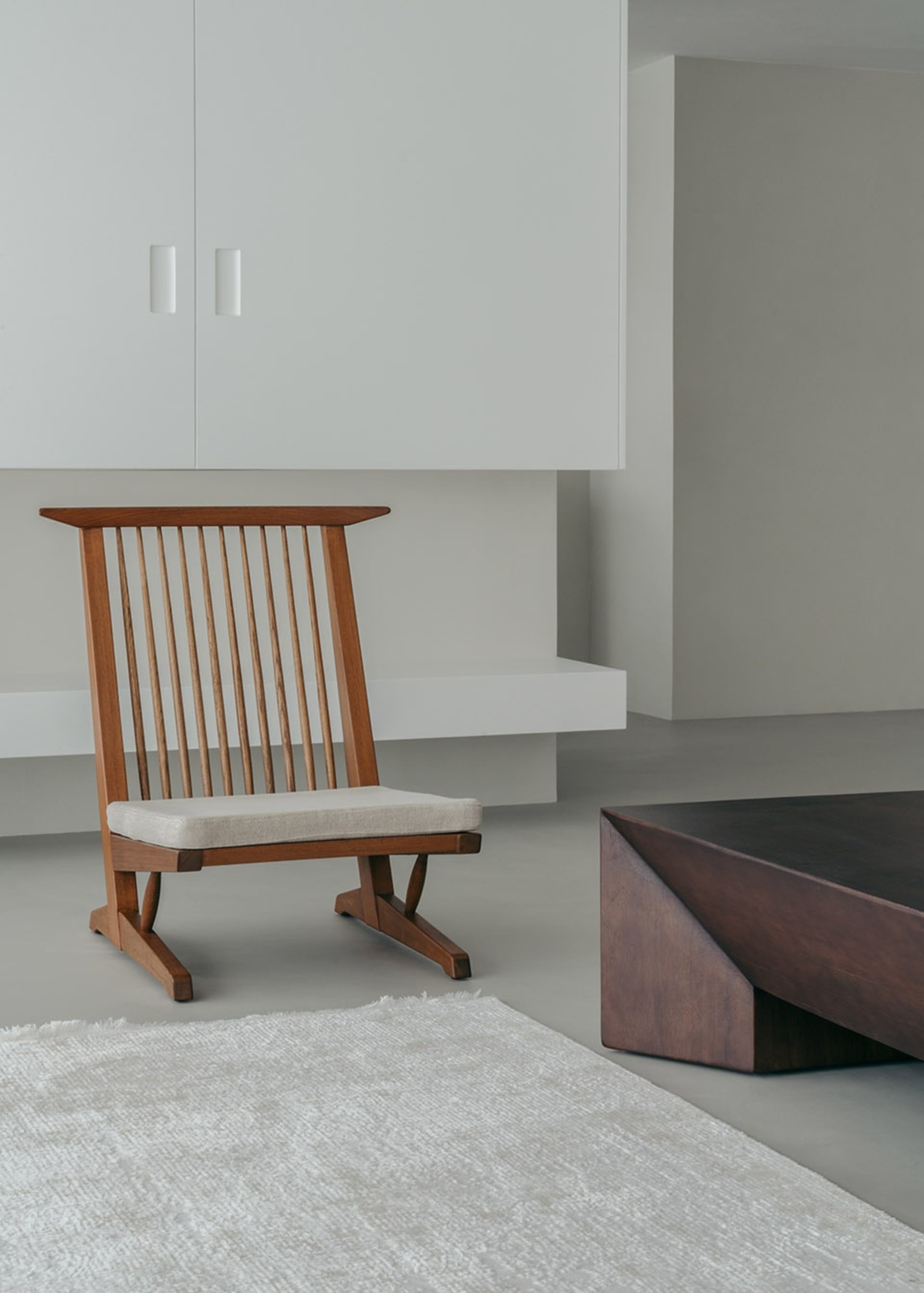 A minimalist living room featuring wooden furniture with a low coffee table and a cushioned chair.