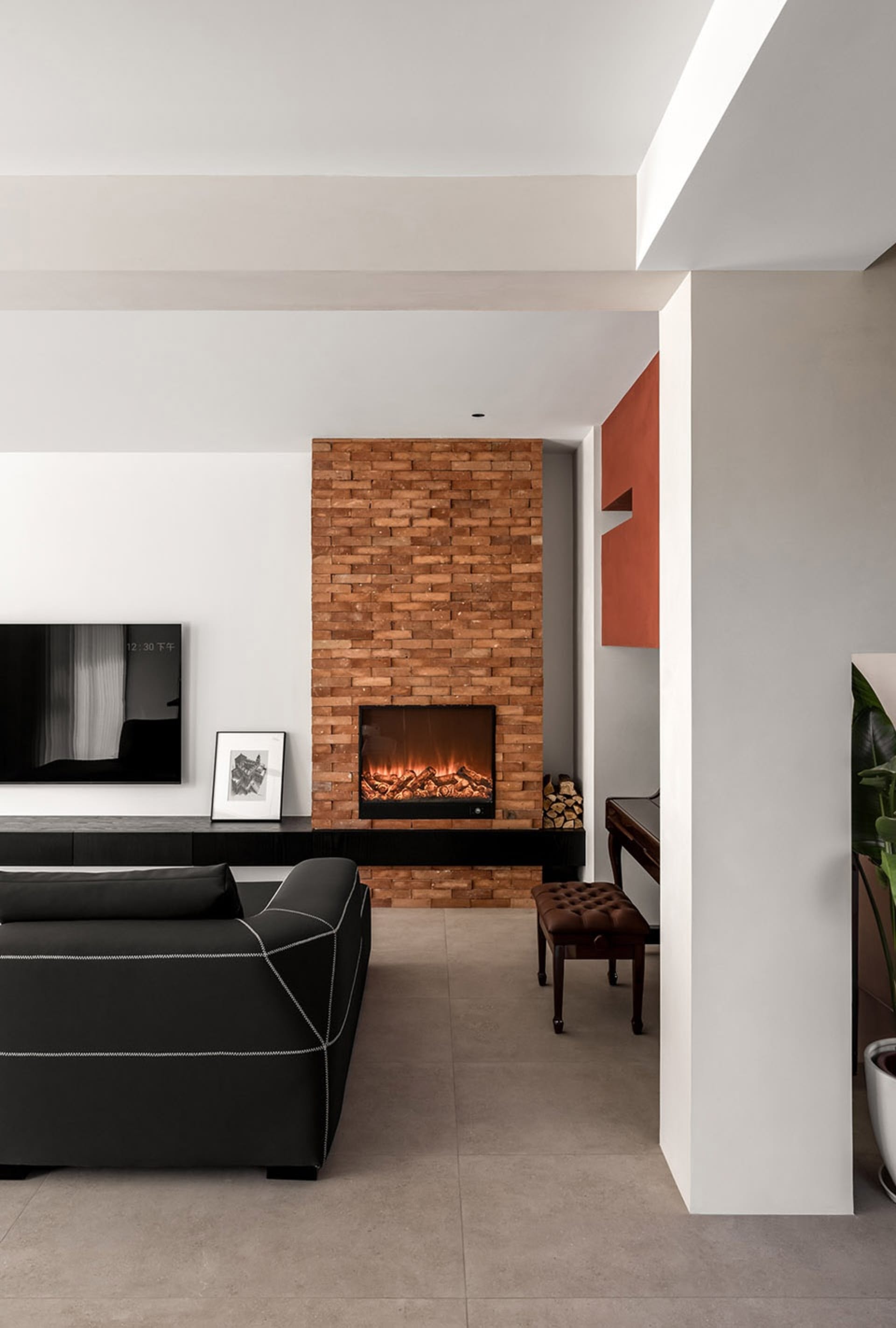 A modern living room featuring a brick fireplace and leather sofa.