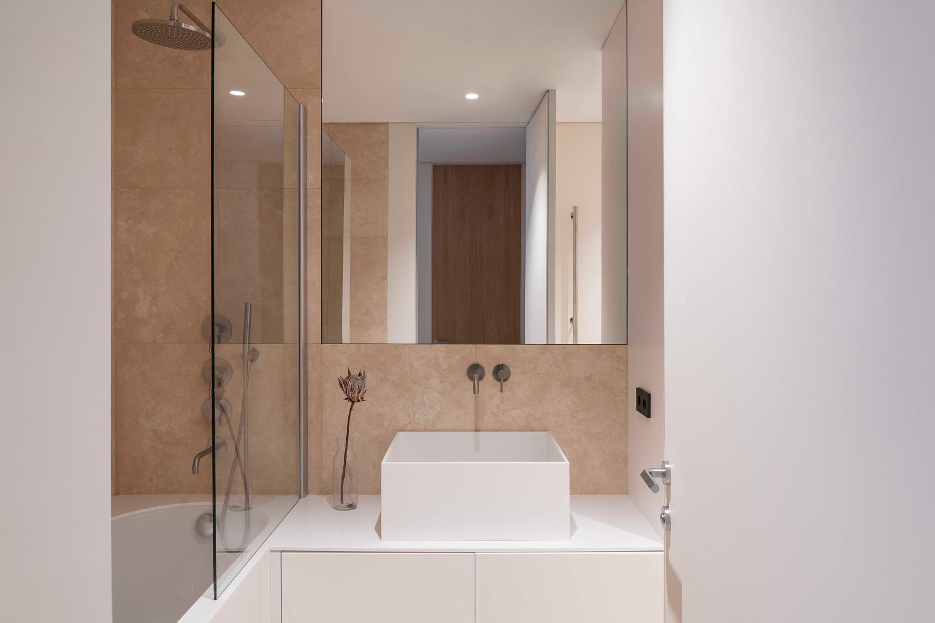 Modern minimalist bathroom featuring ceramic tiles and a white acrylic sink against a beige backdrop.