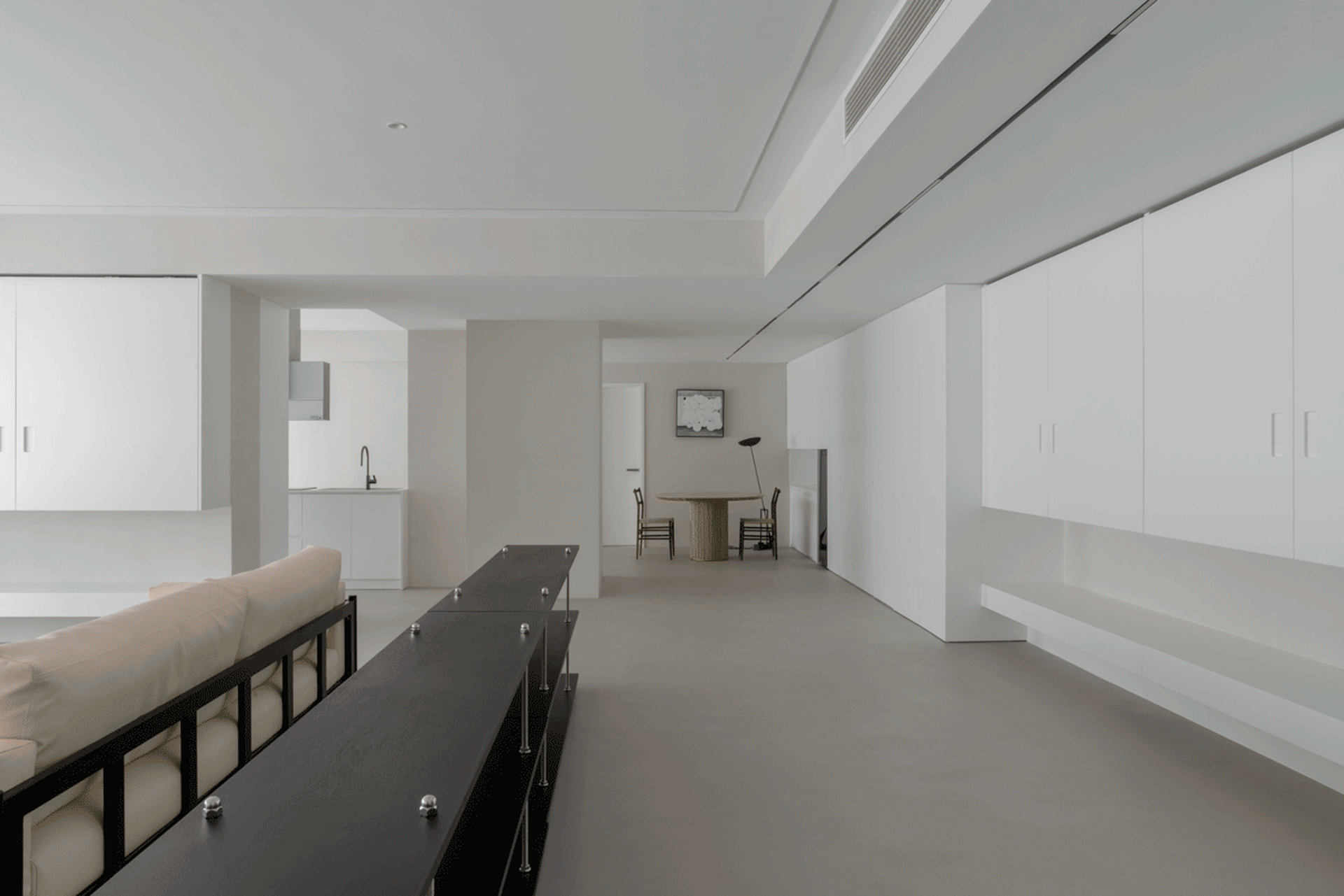 Modern, open-plan living room with minimalist white furniture, designed for spacious and airy living.