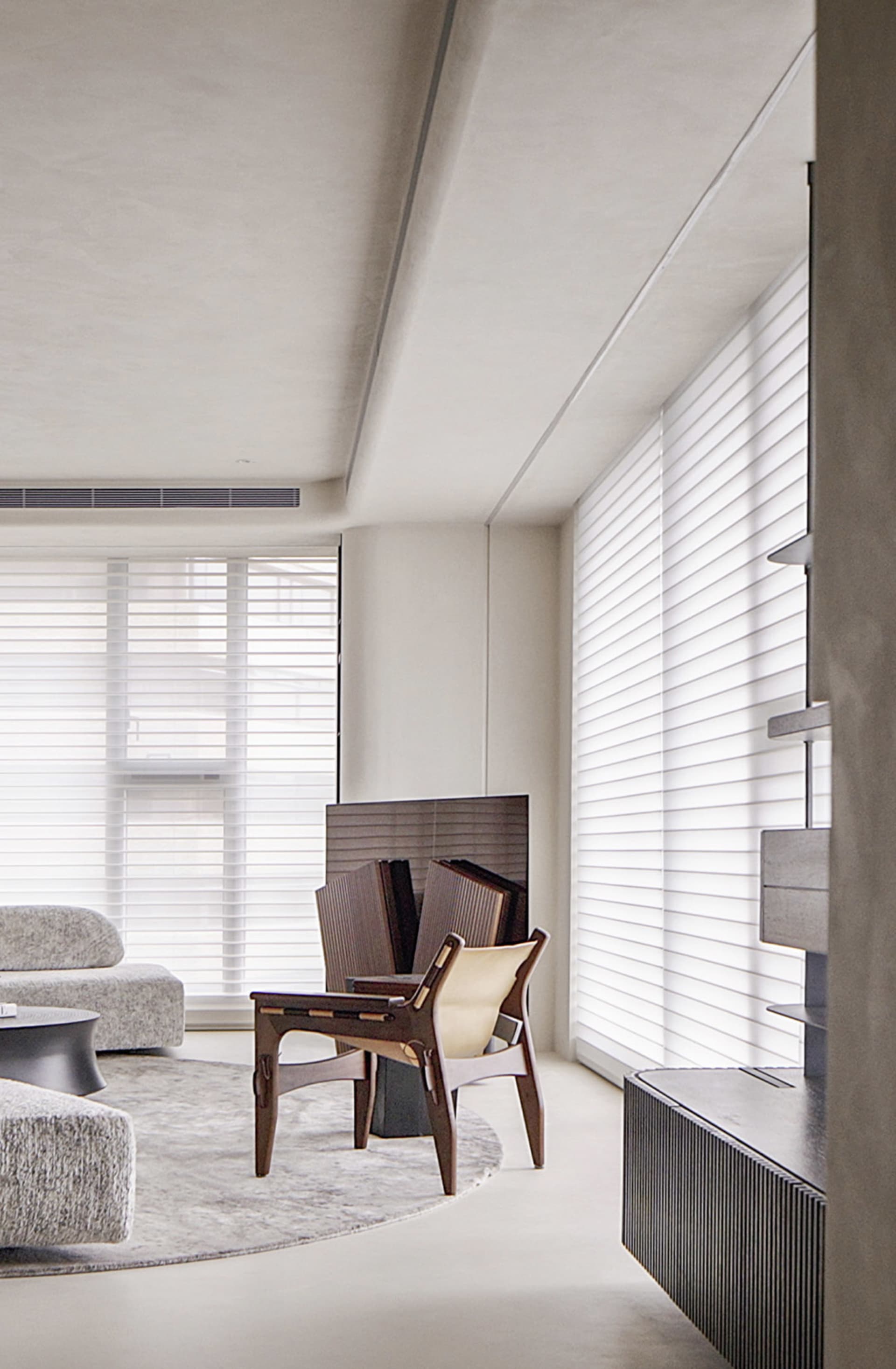 A minimalist living room with neutral-toned furniture, a rug, and large windows with blinds.