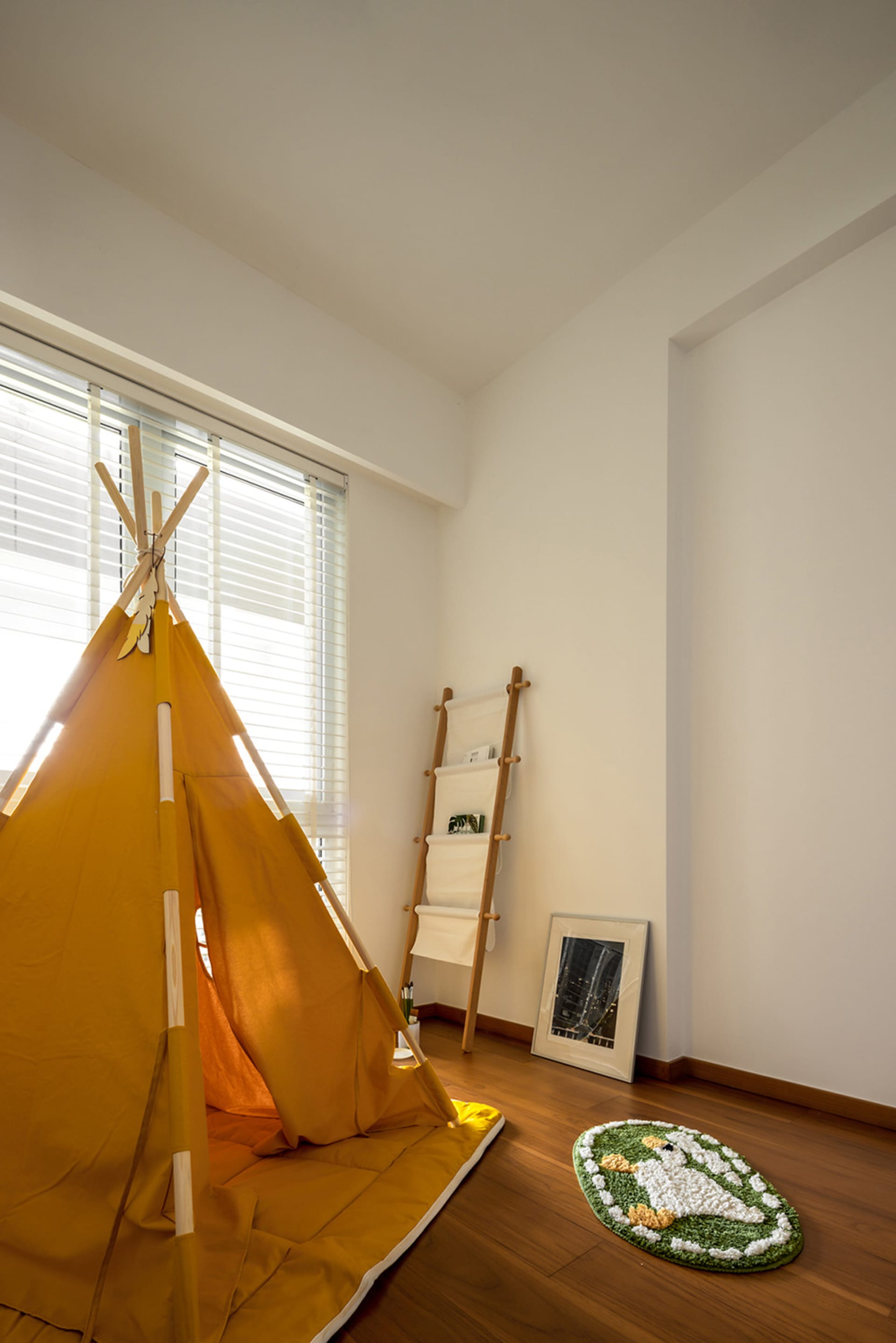 A yellow children's play tent set up indoors with a ladder, rug, and window with blinds.