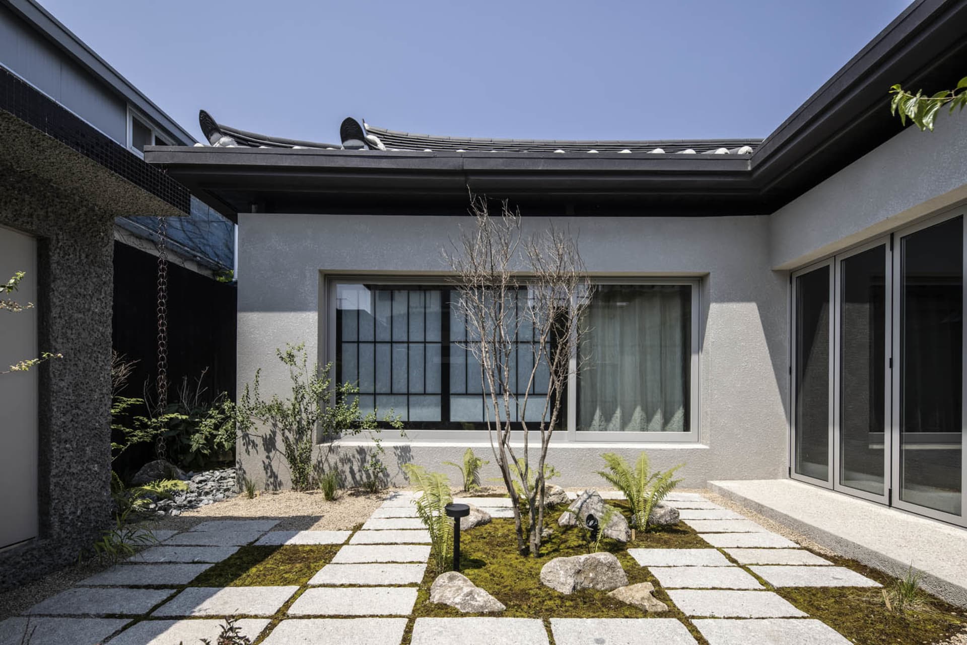 Minimalist residential courtyard featuring modern concrete and glass materials.