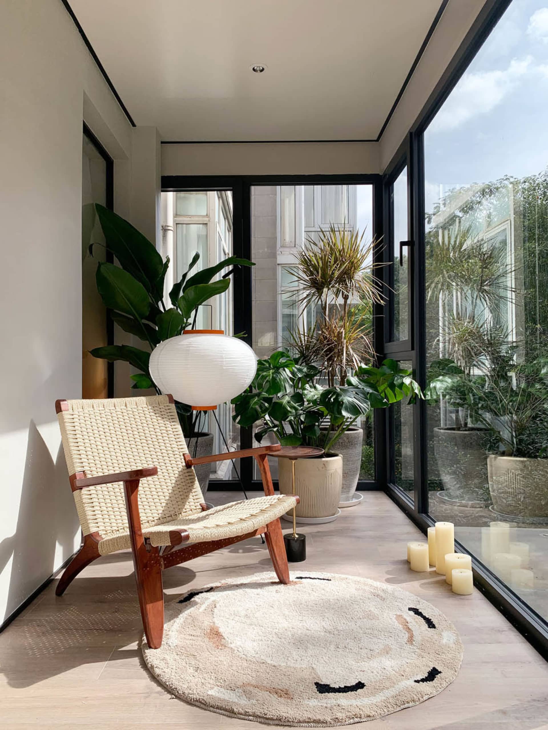Modern minimalist living space featuring wood furniture, potted plants, and concrete flooring.