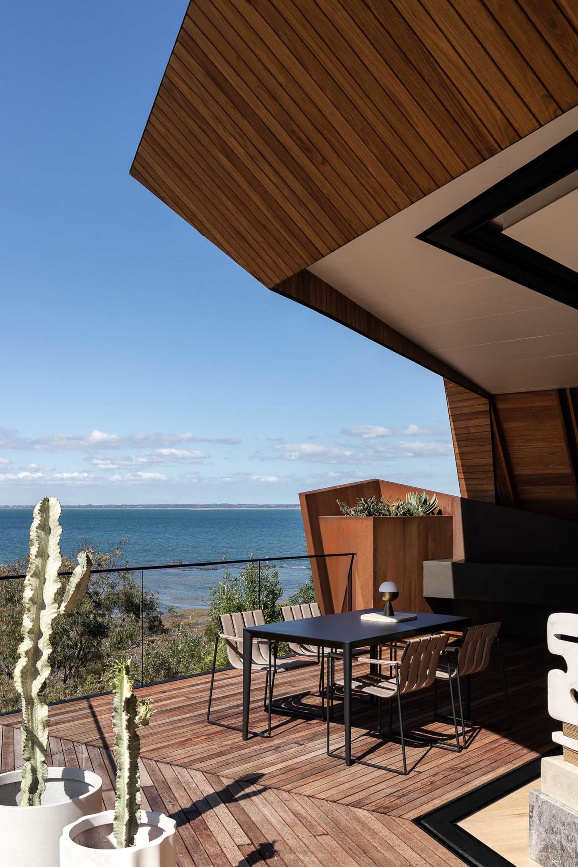 Industrial-style residential balcony featuring timber wood with views of the ocean.