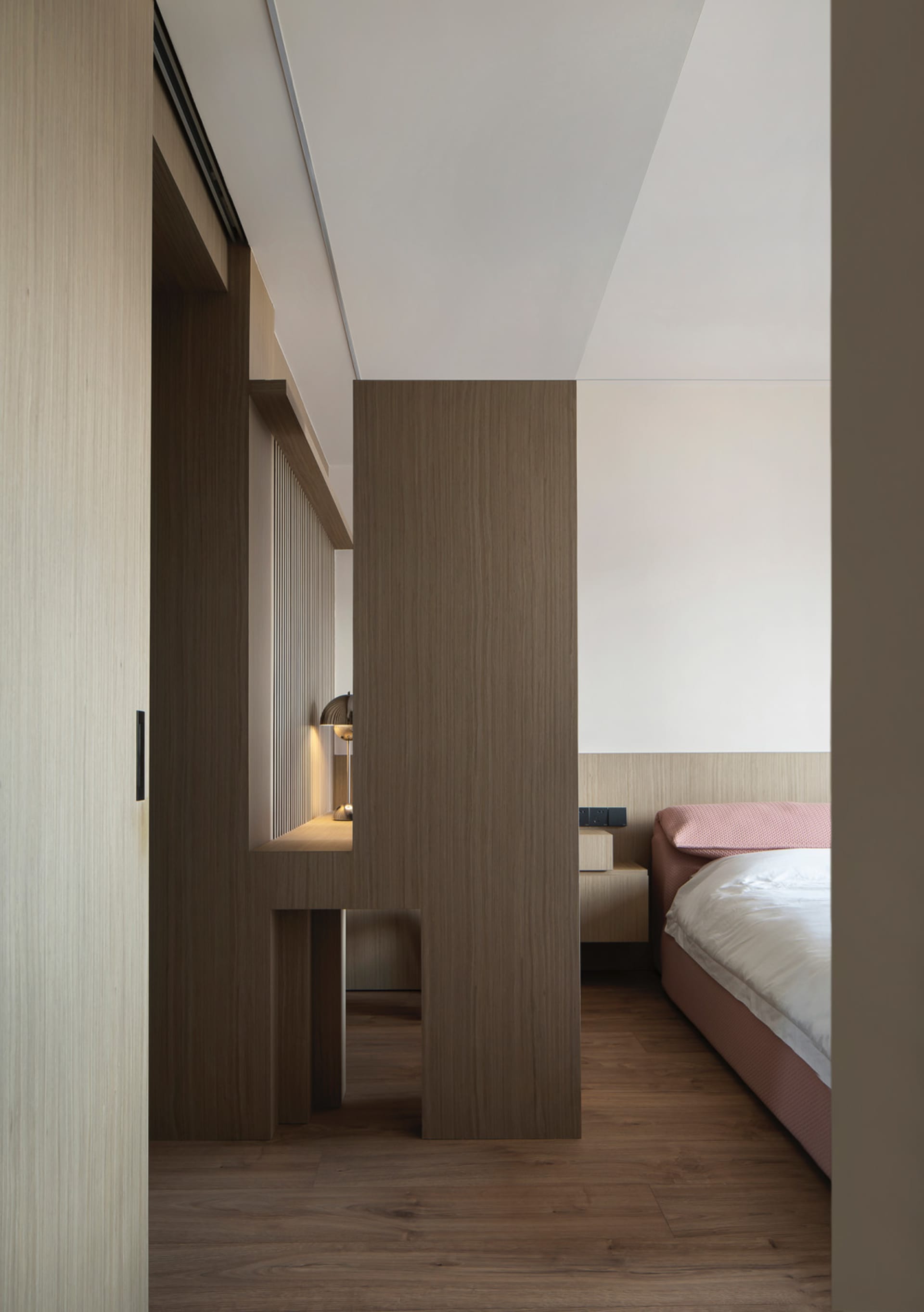 A minimalist bedroom featuring wooden furniture and floors.