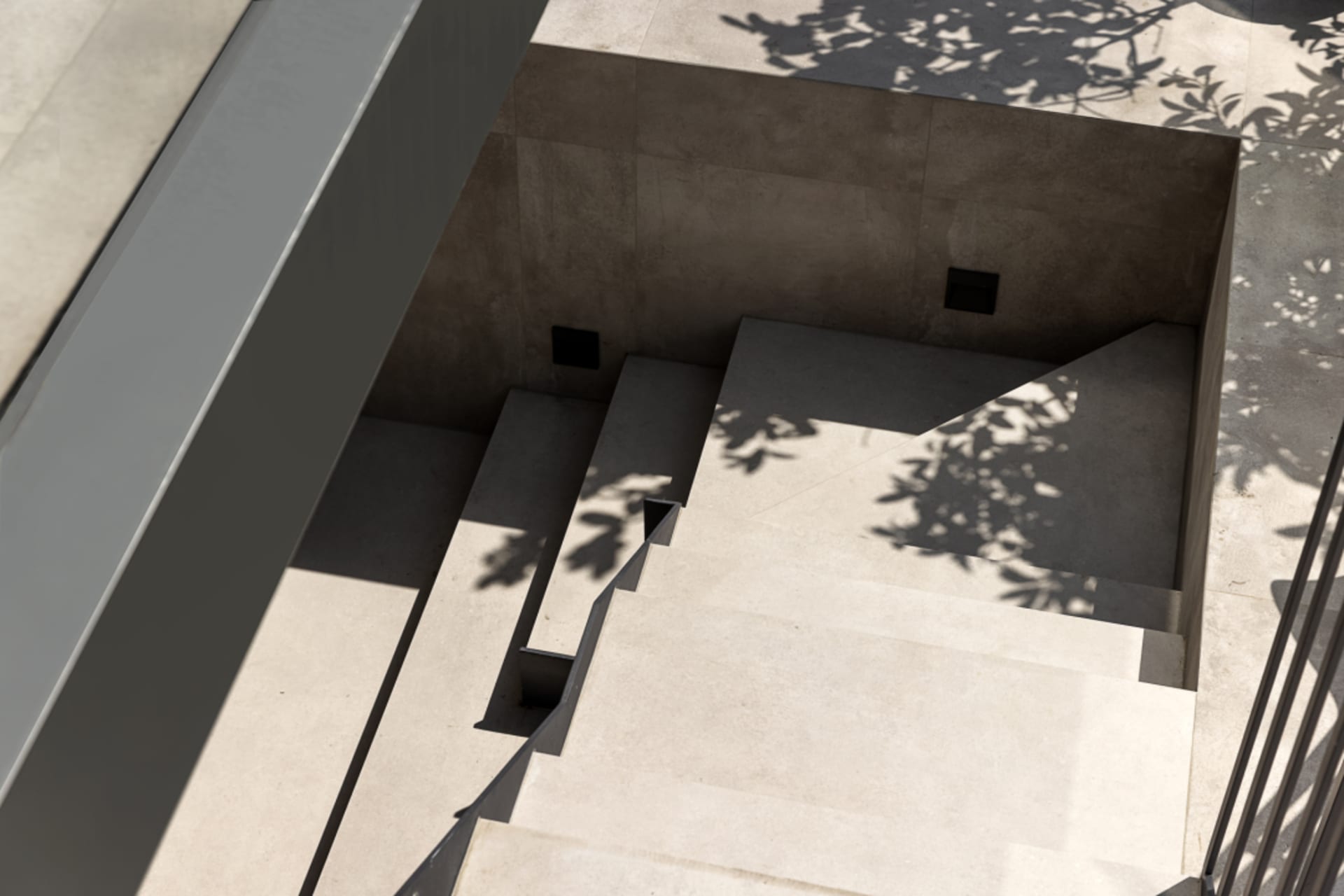 A minimalist concrete space featuring a set of stairs with shadows of trees.