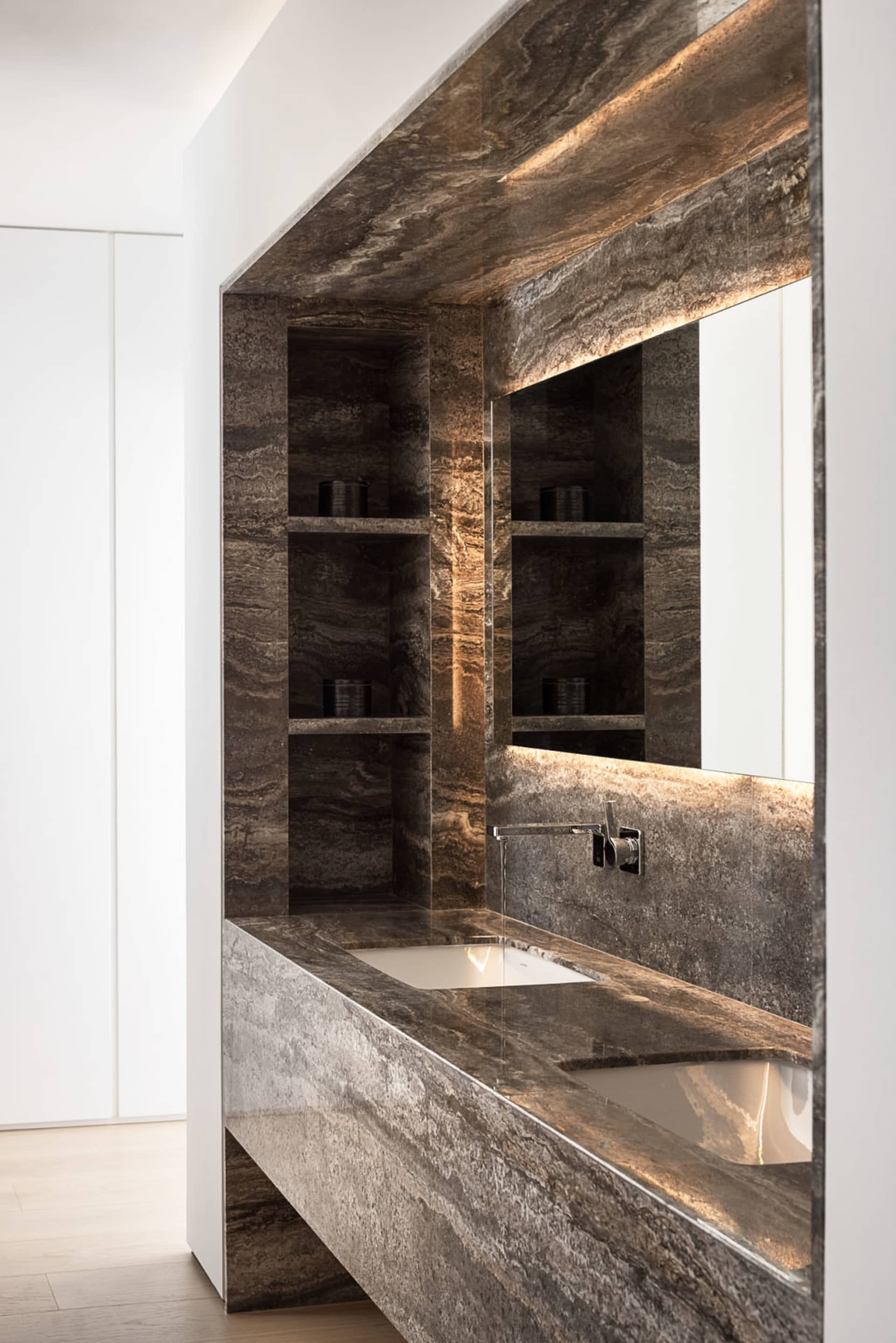Modern minimalist bathroom with granite countertops, a sleek white sink, and an illuminated mirror.
