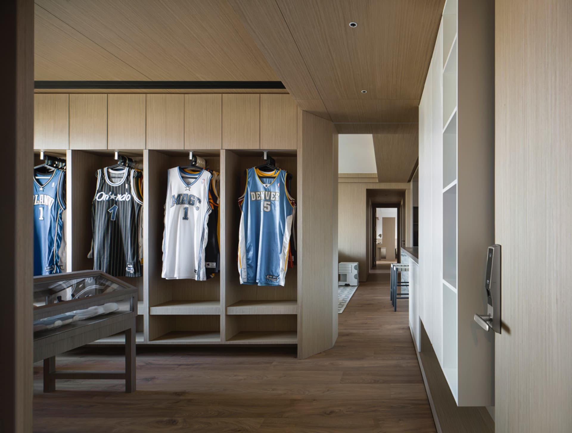 Wooden closet with jerseys hanging on shelves.