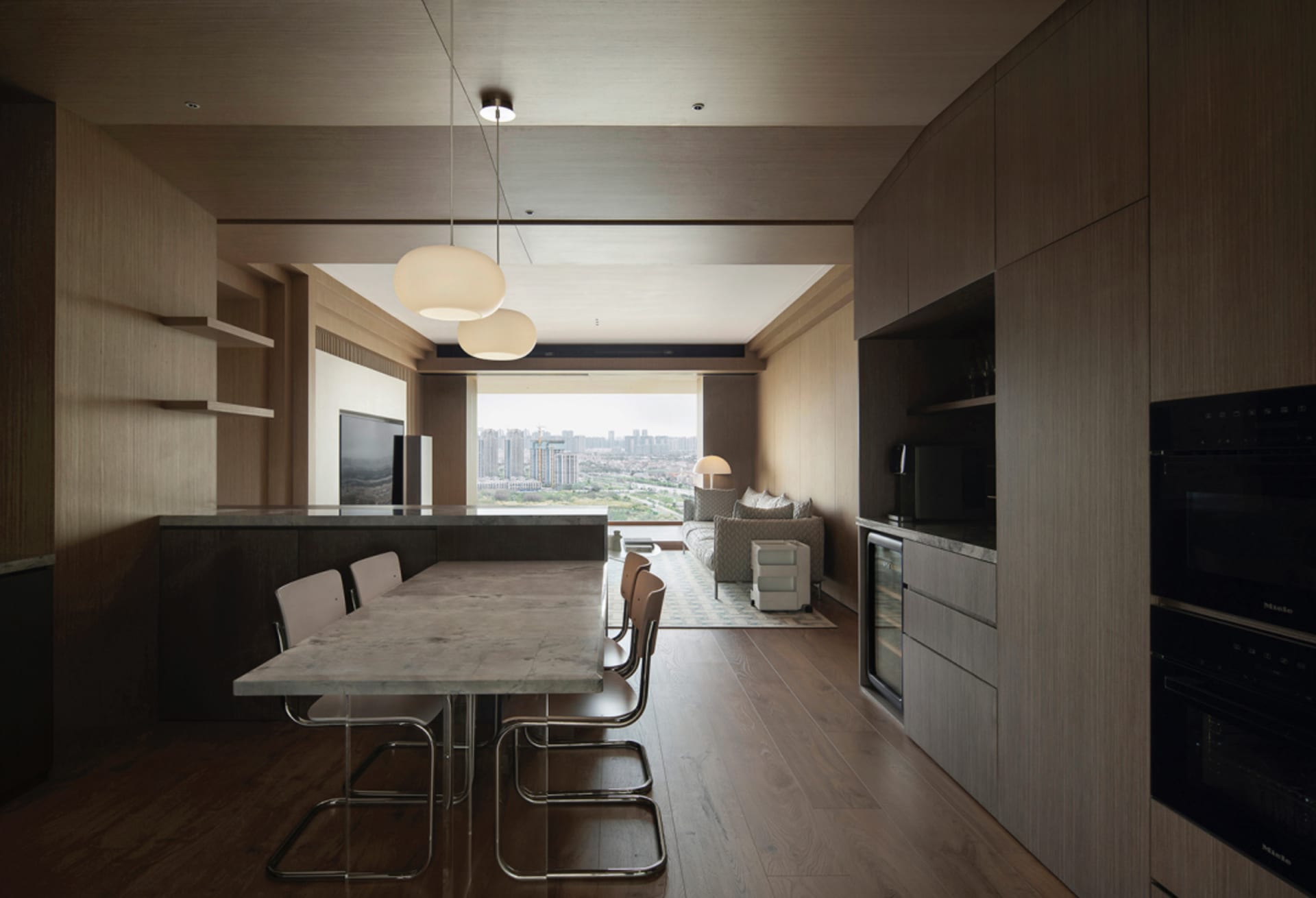Modern apartment featuring a stone-top dining table and minimalist furniture, with a view of the cityscape.