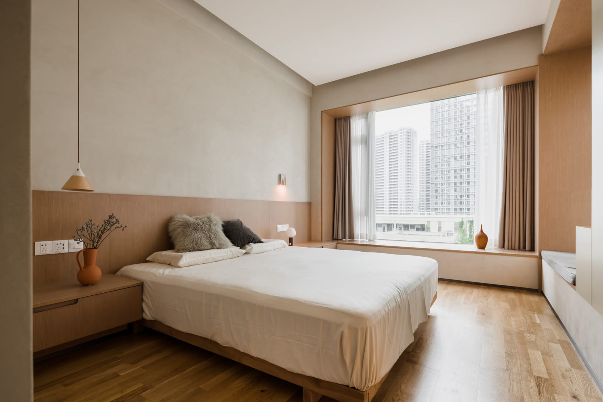 A modern minimalist bedroom featuring wooden furnishings and a large window overlooking a cityscape.