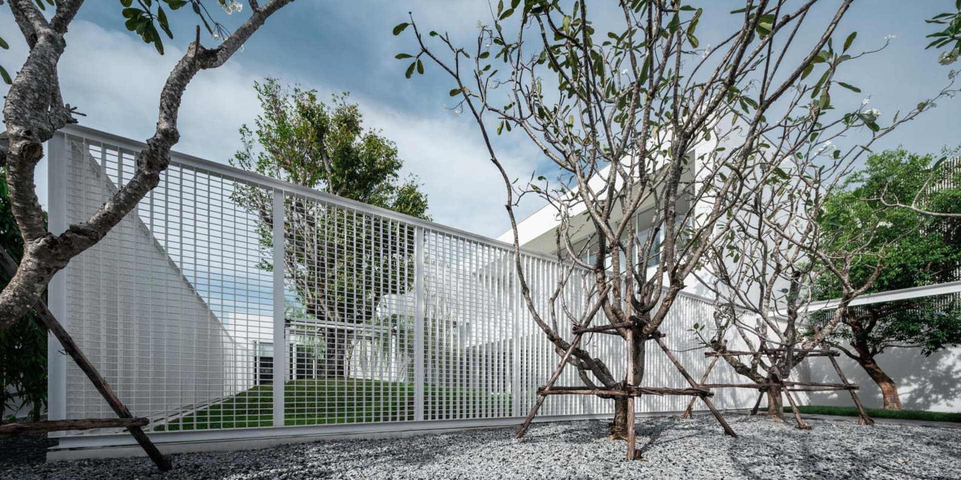 Modern residential design featuring metal fencing, concrete patio, and gravel ground cover.