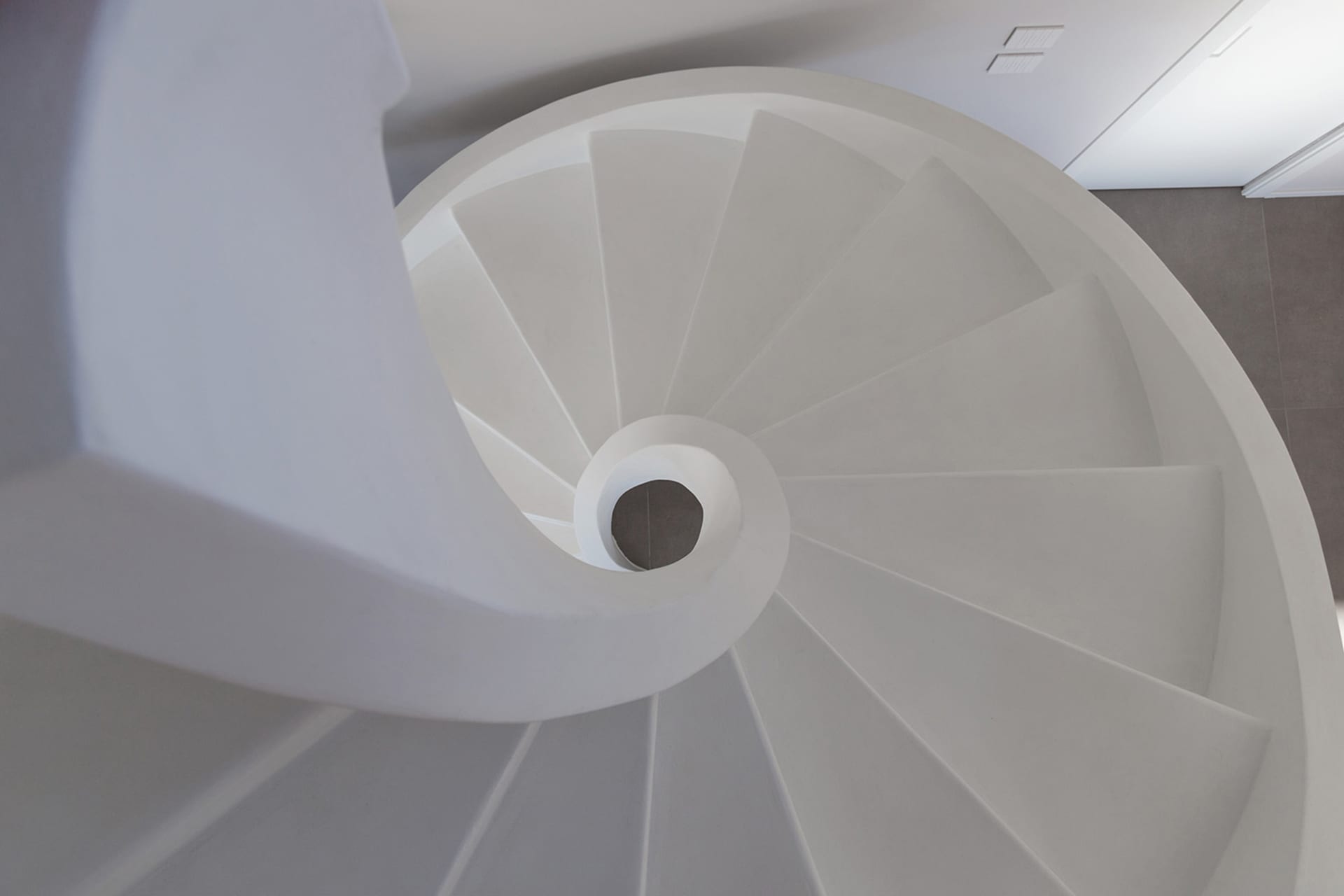 A minimalist white spiral staircase constructed from concrete.