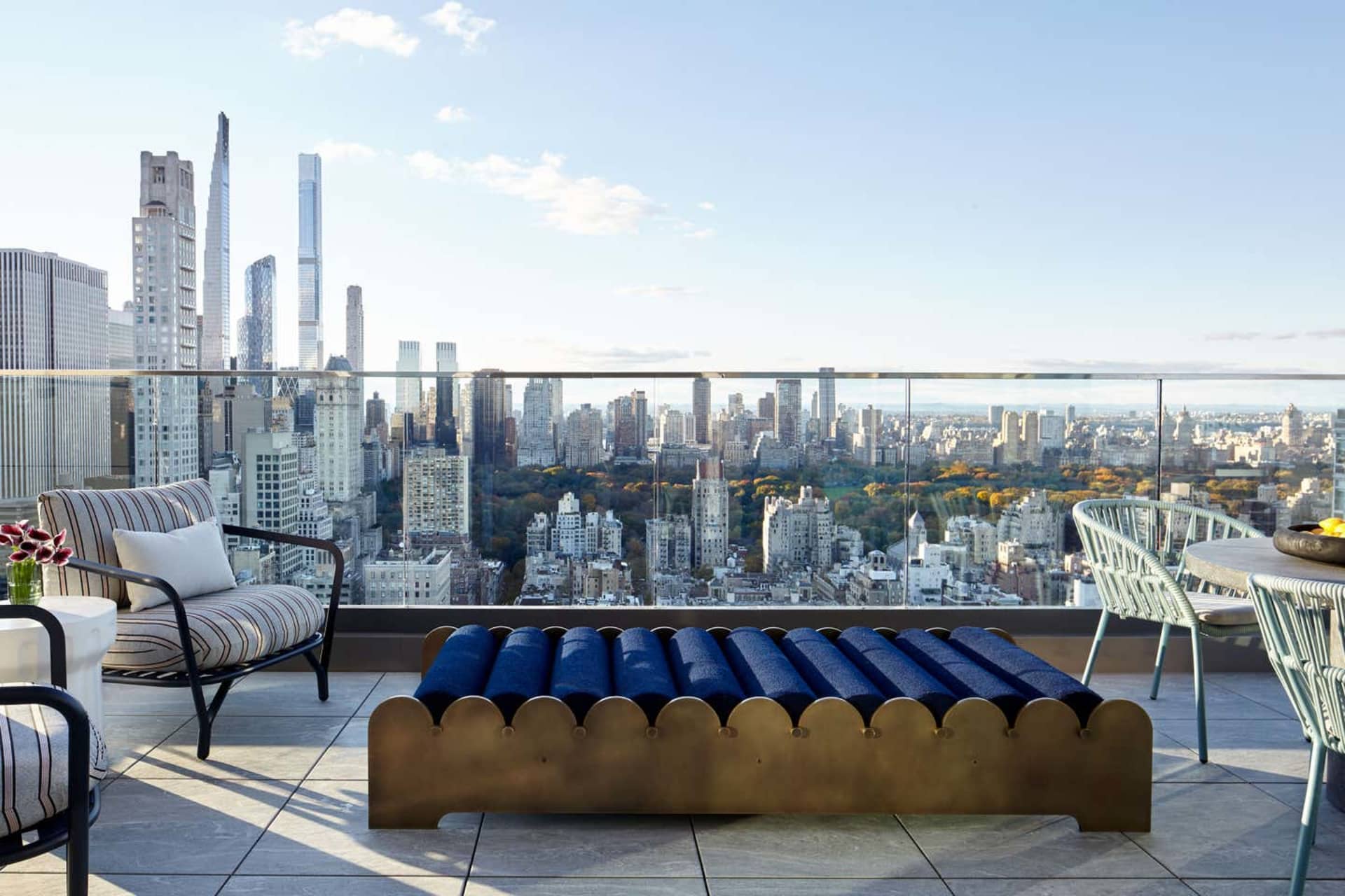A rooftop terrace with a metal and glass barrier overlooking a cityscape.