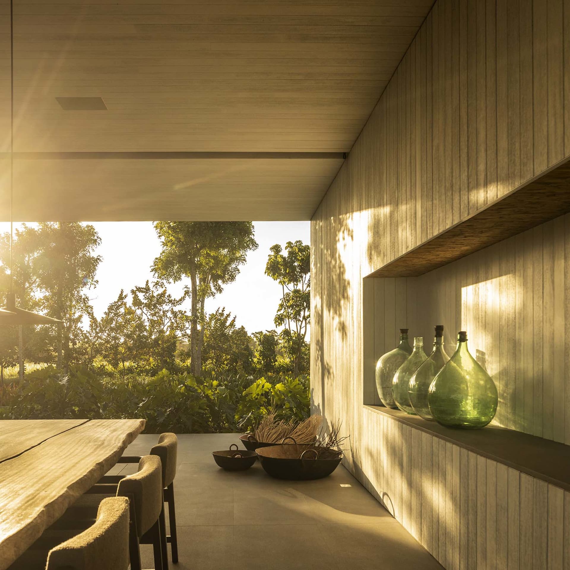 A modern dining room with bamboo furniture and minimalist decor, featuring a large table and chairs under natural sunlight.